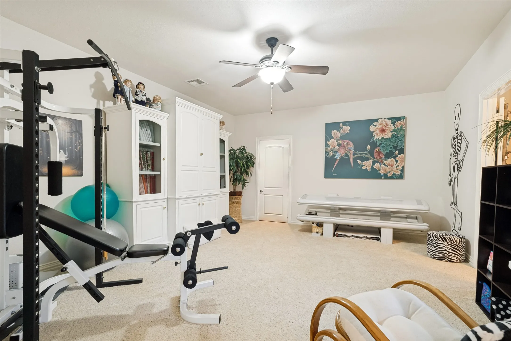 Spacious carpeted room featuring a ceiling fan, a built-in white cabinetry unit, and a white paneled door