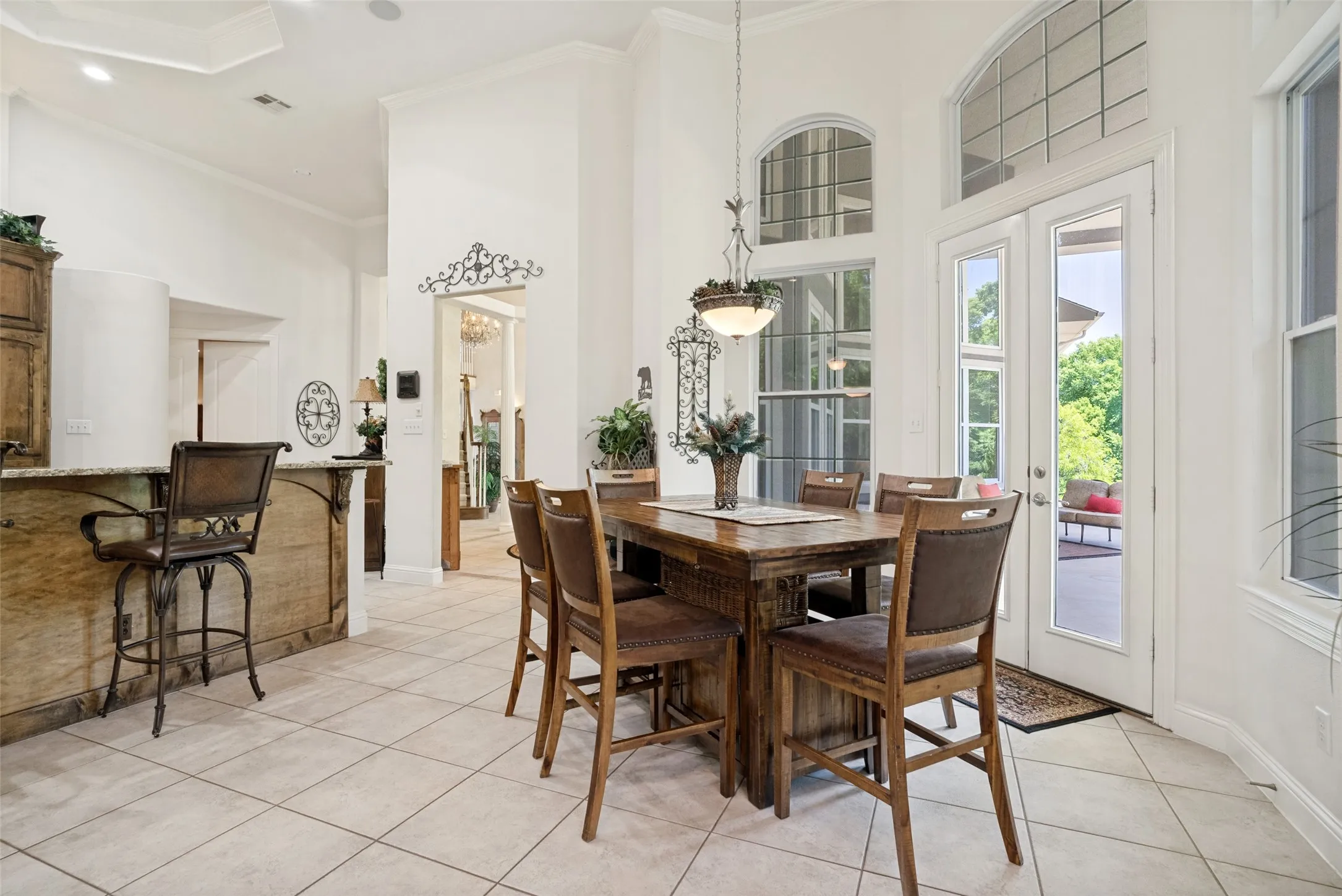 Tiled dining area featuring French doors, a transom window, and a built-in breakfast bar with a stone countertop