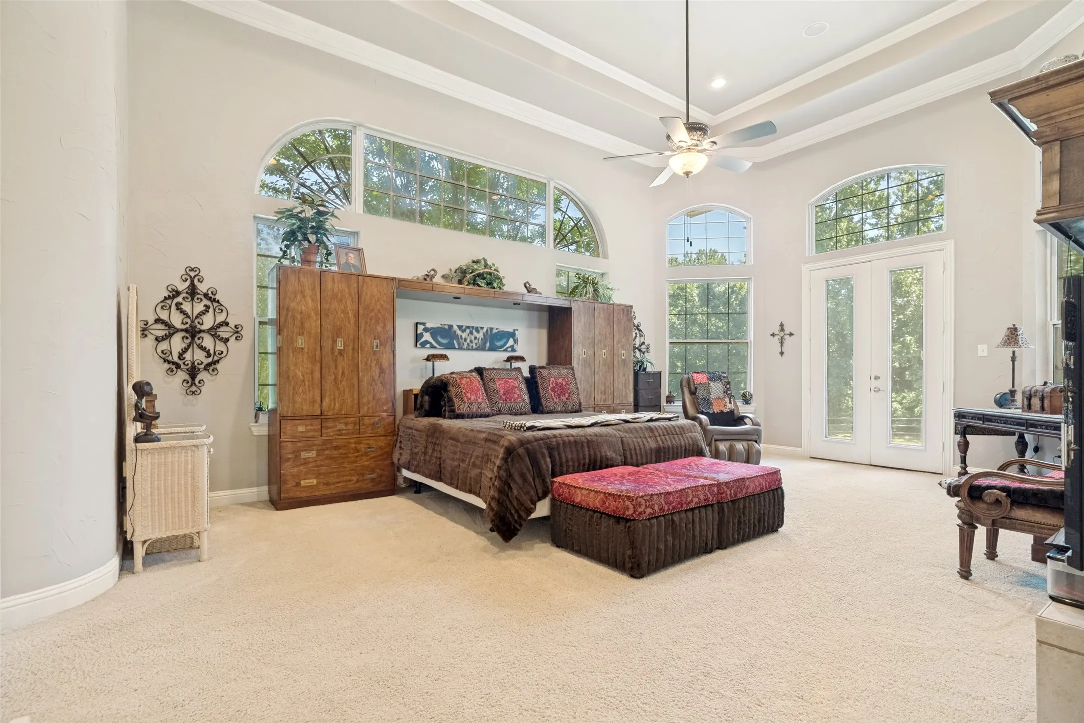 Expansive room featuring high vaulted ceilings with decorative beams, arched transom windows, a ceiling fan, and carpeted flooring