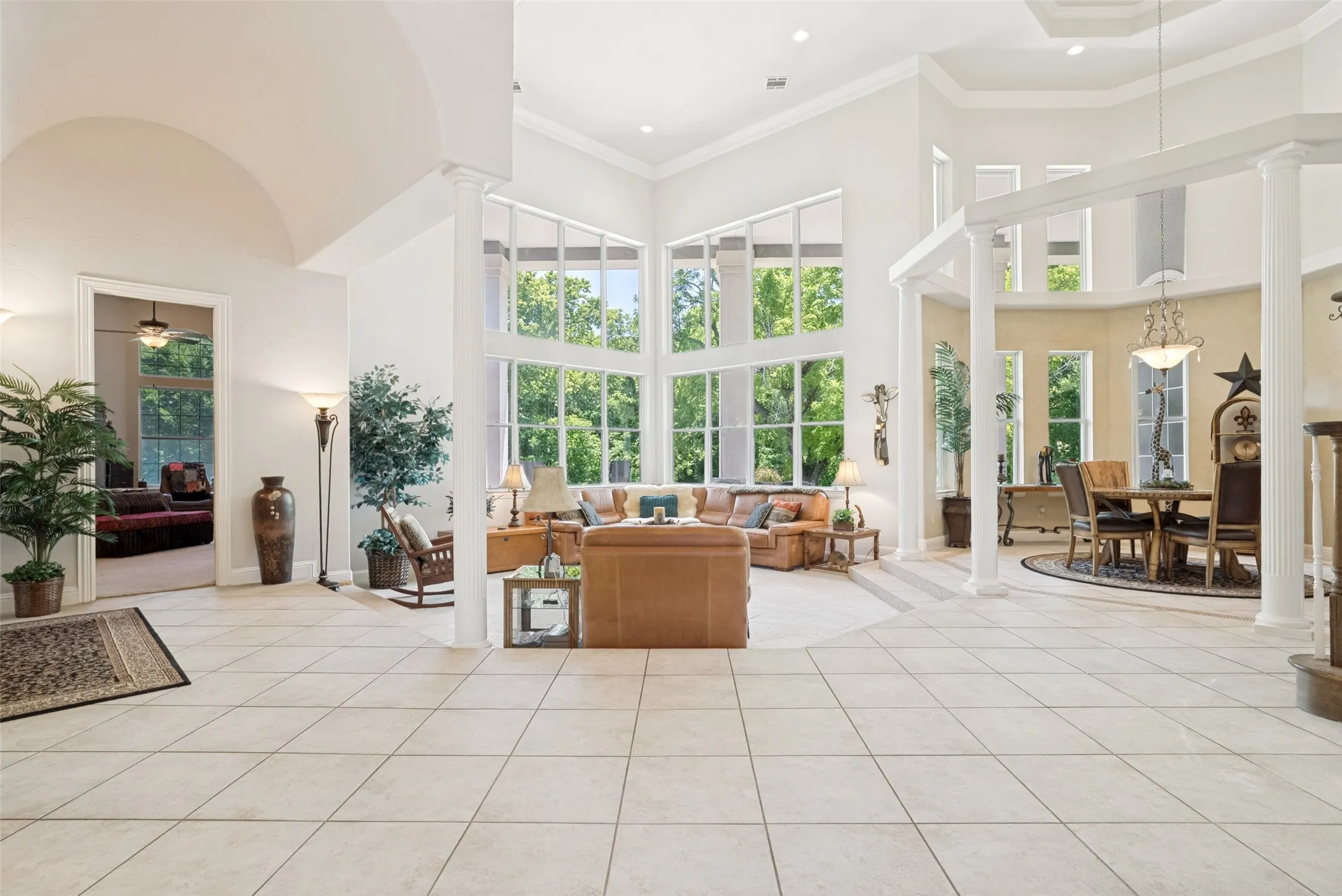 Grand foyer featuring light-toned tile flooring, soaring vaulted ceilings, and architectural columns