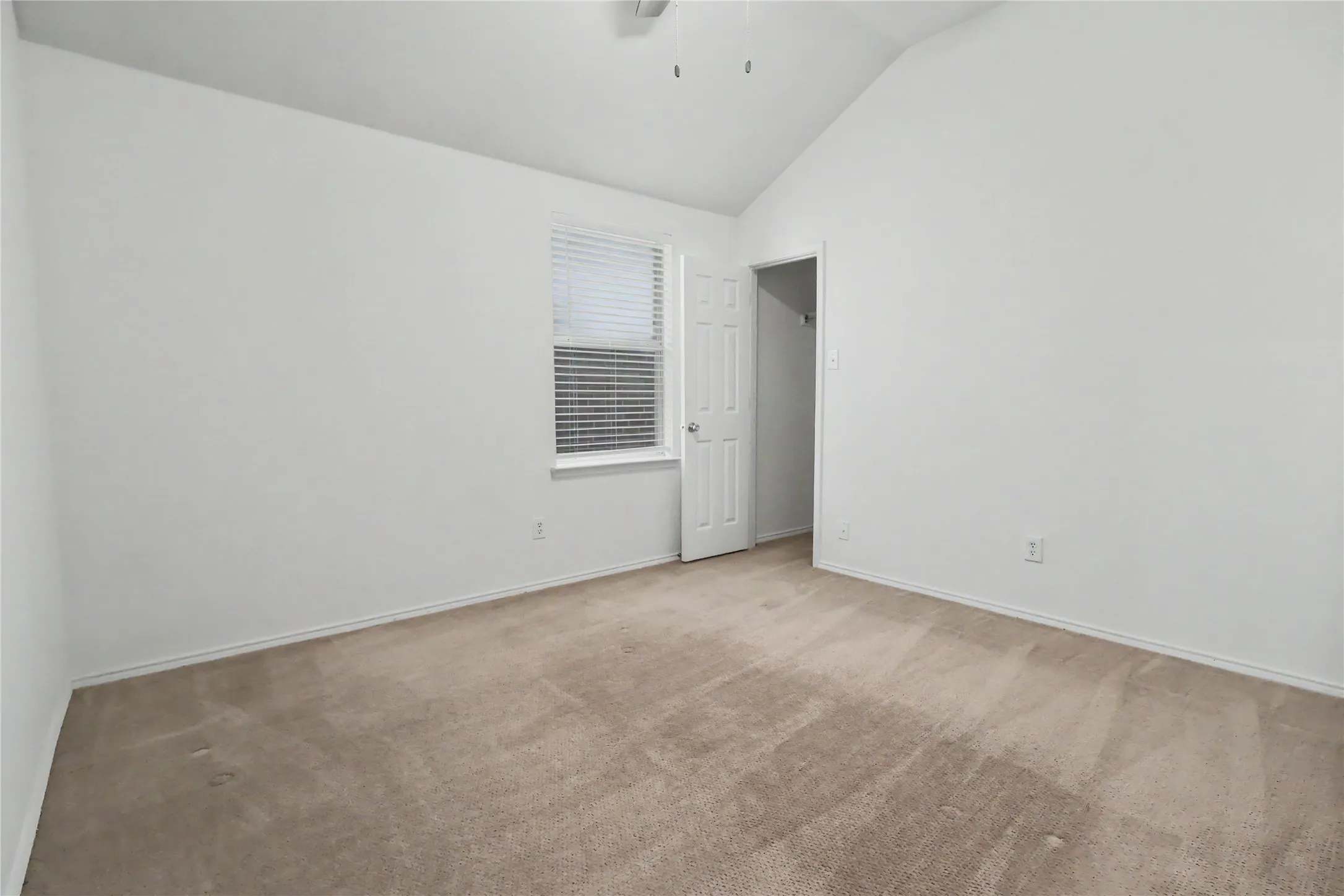 Carpeted room featuring a vaulted ceiling and a ceiling fan