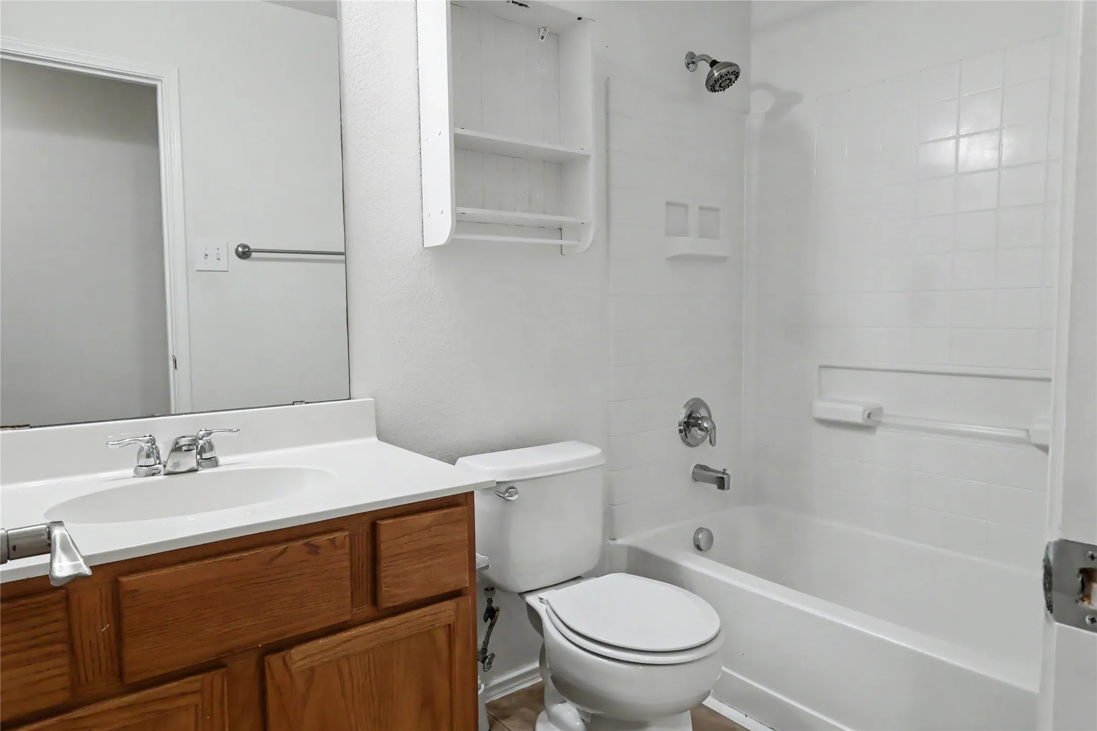 Bathroom featuring a wood-finish vanity with a white countertop and integrated sink, chrome faucet, and a large wall-mounted mirror