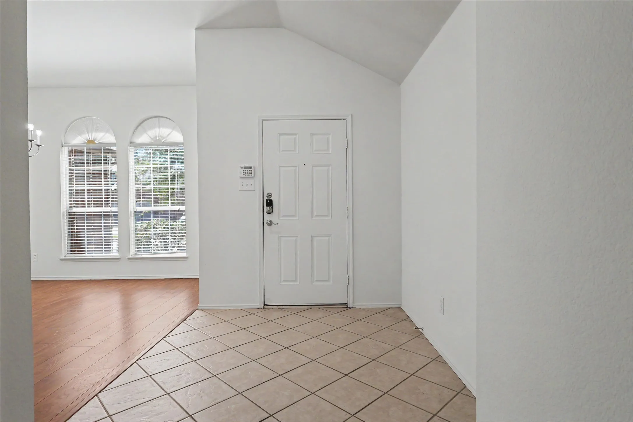 Entryway featuring tile flooring, a paneled door, and vaulted ceilings