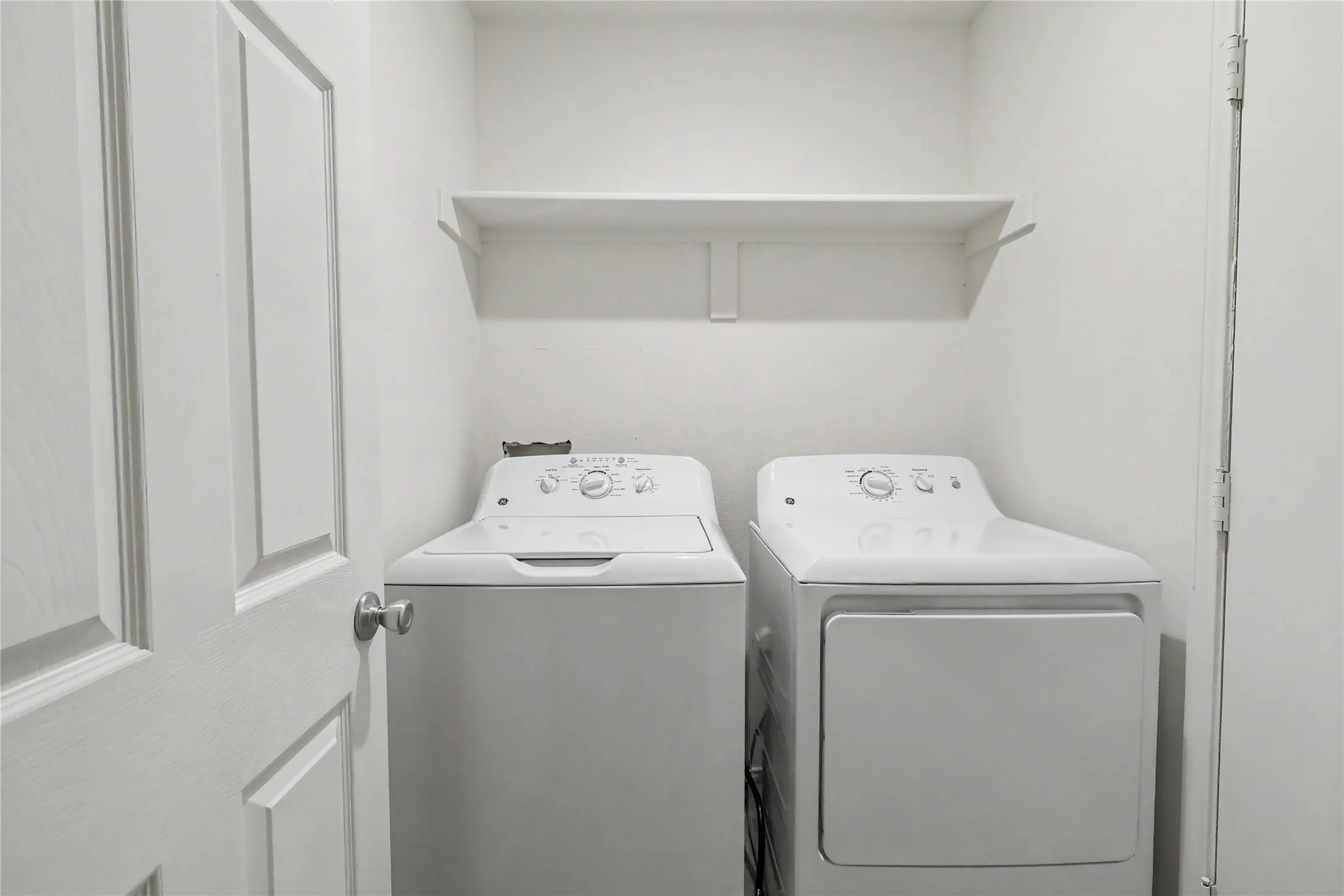 Dedicated laundry space featuring a white top-load washing machine and front-load dryer