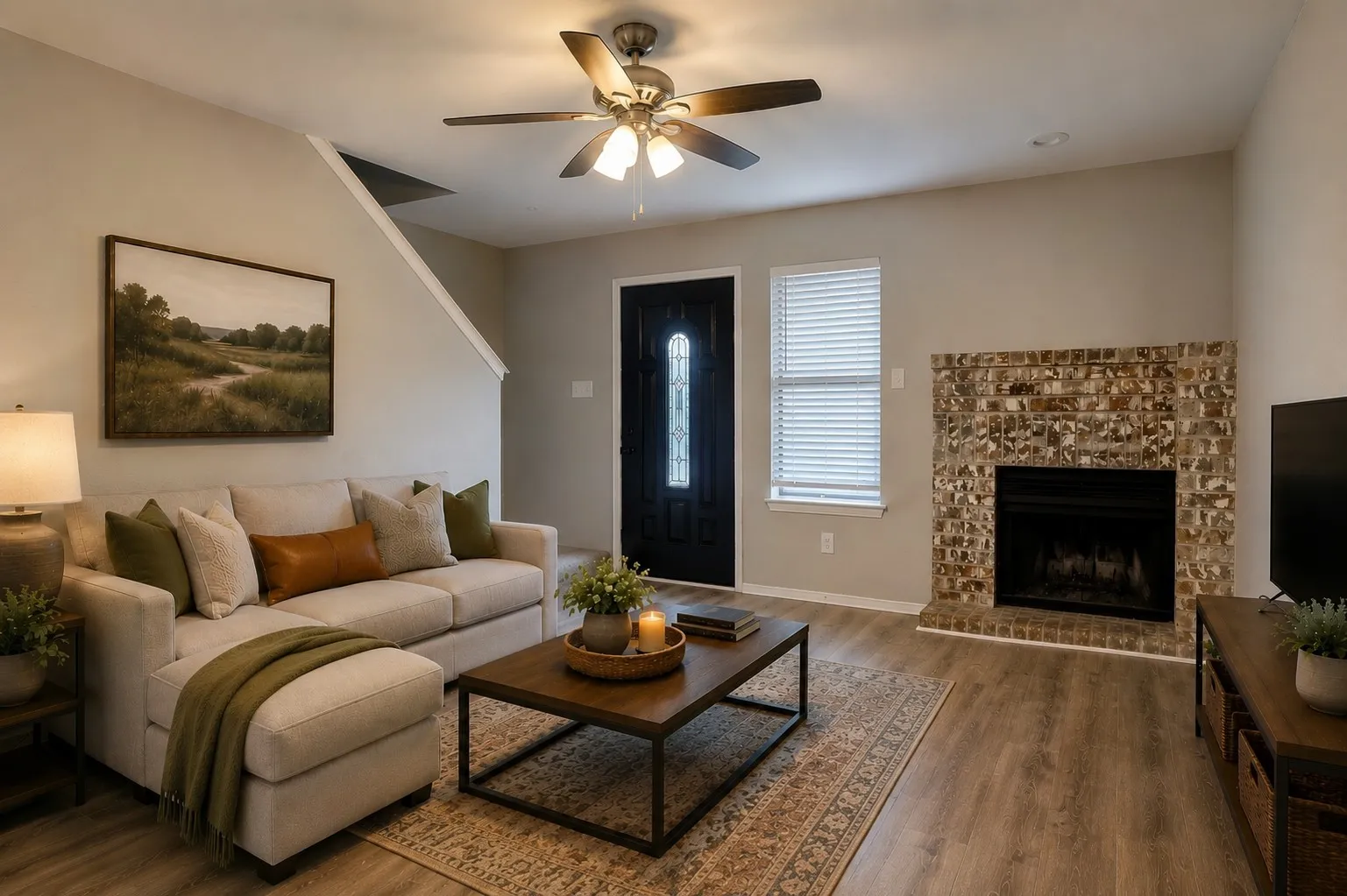 Virtually staged. Living area featuring wood-finish flooring, a brick fireplace, ceiling fan with integrated lighting, and a dark paneled entry door