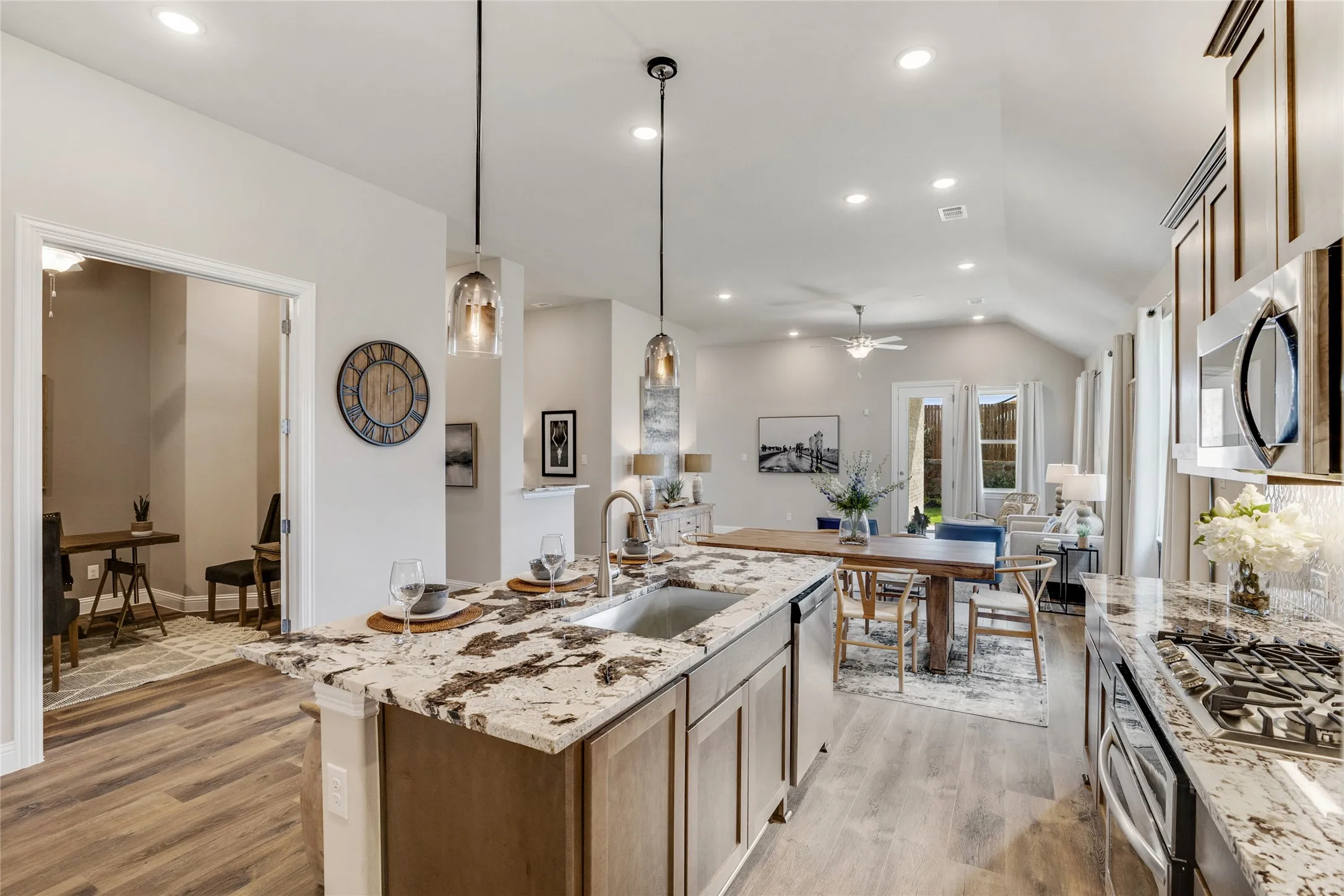 Open-concept kitchen with a large island featuring an undermount sink, granite countertops, and pendant lighting