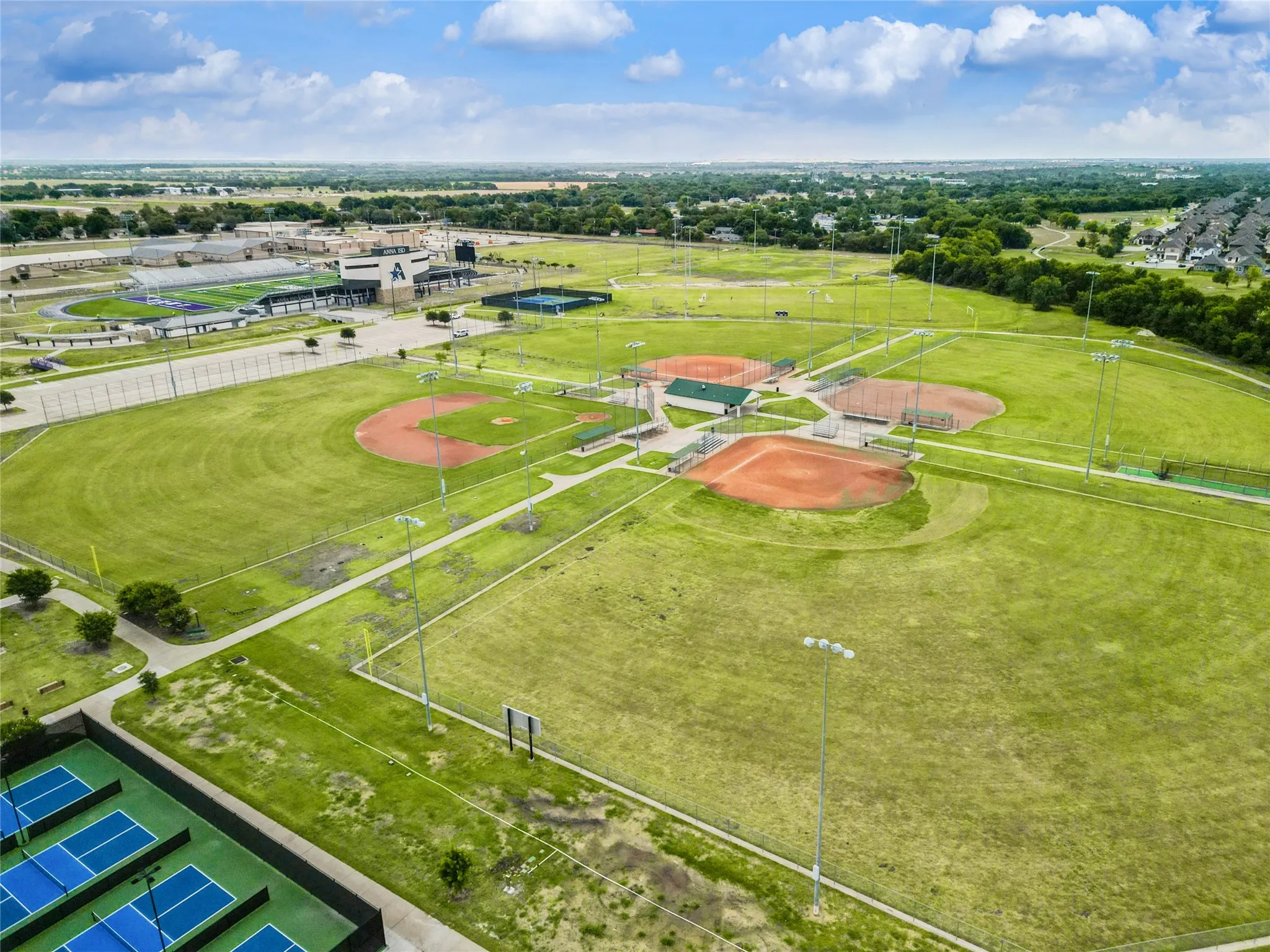 Extensive sports complex featuring multiple baseball diamonds, a tennis court area, and a large athletic stadium