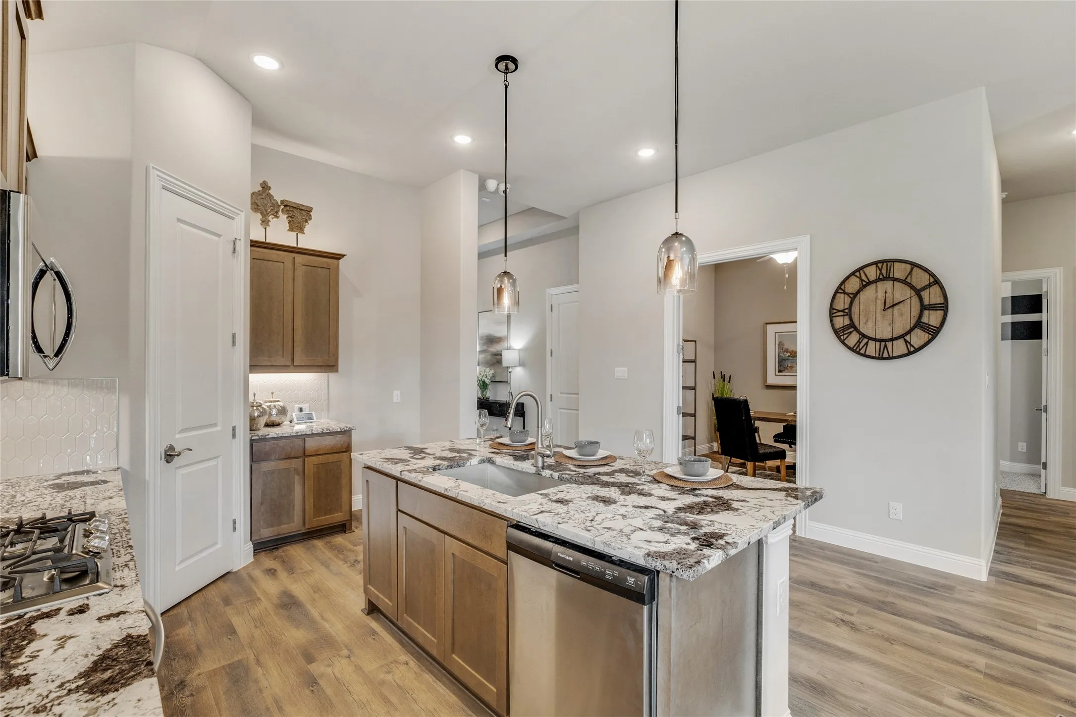 Kitchen island featuring a stainless steel undermount sink, pendant lighting, and granite countertops