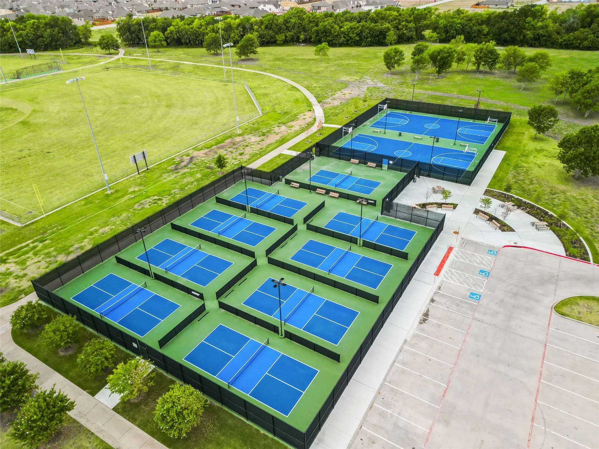 Community recreation area featuring multiple pickleball courts, basketball courts, and expansive green spaces