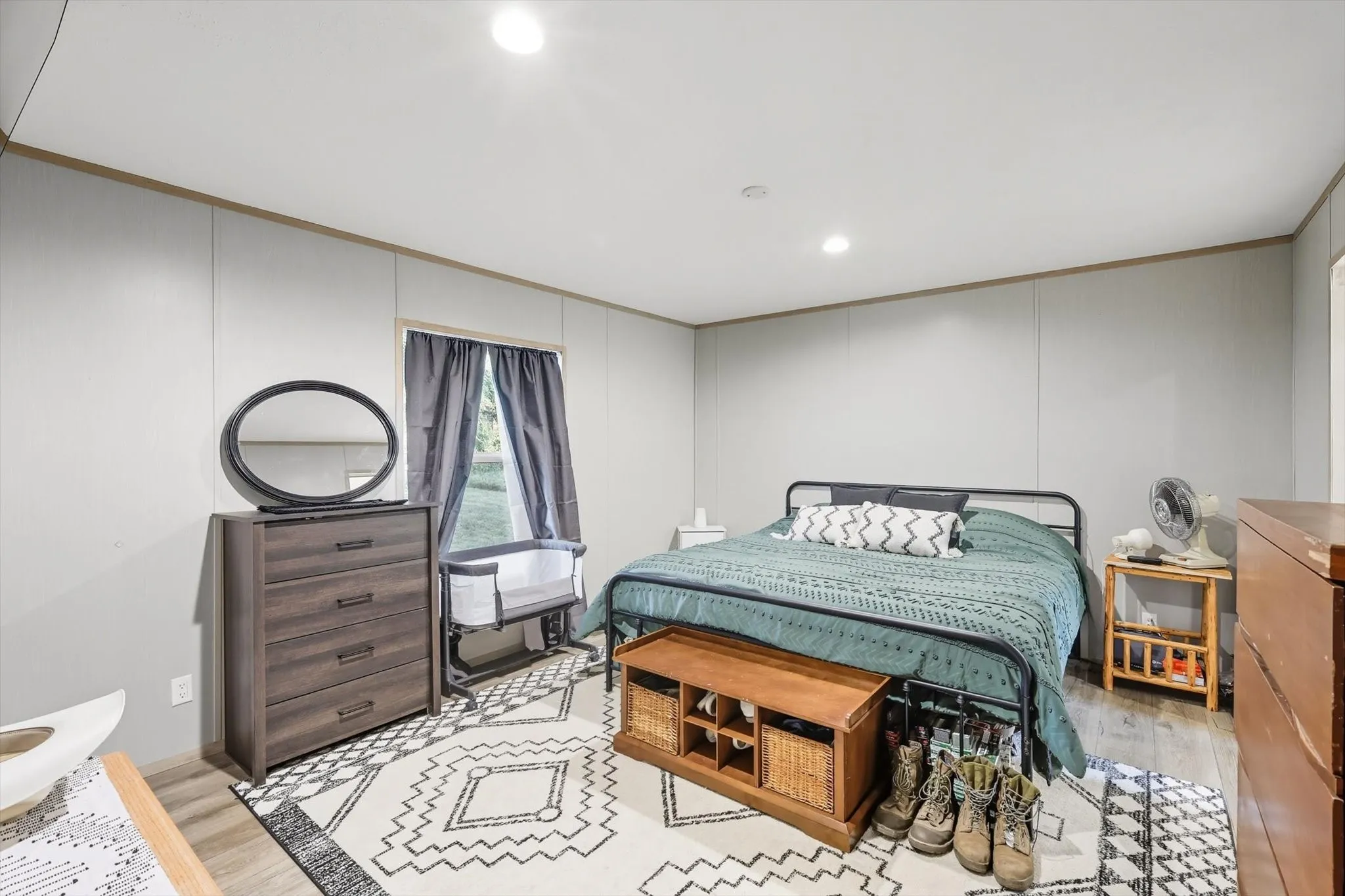 Bedroom with light wood-type flooring, ornamental molding, recessed lighting, and a decorative wall