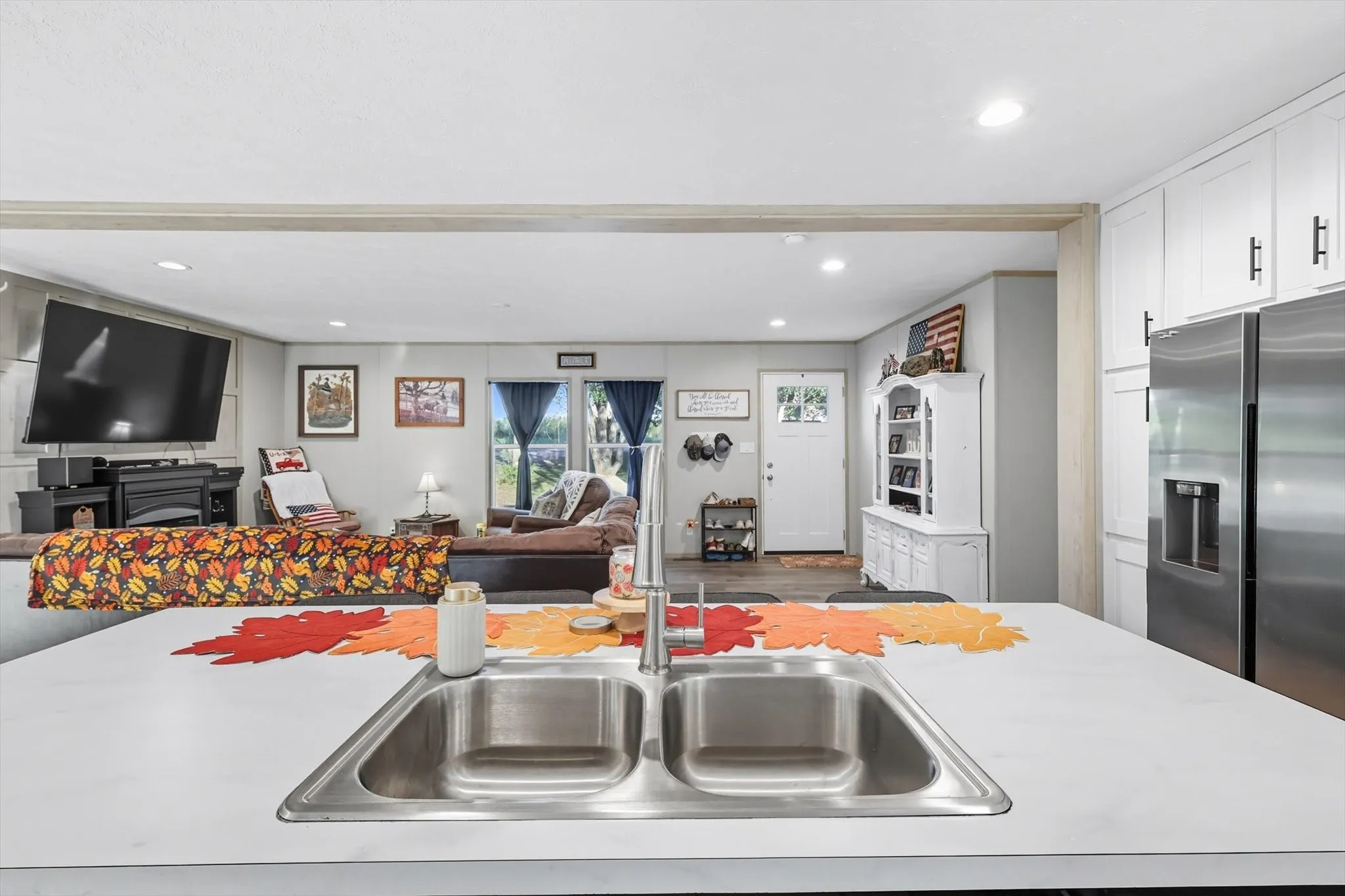 Kitchen featuring open floor plan, light countertops, stainless steel fridge with ice dispenser, recessed lighting, and white cabinets