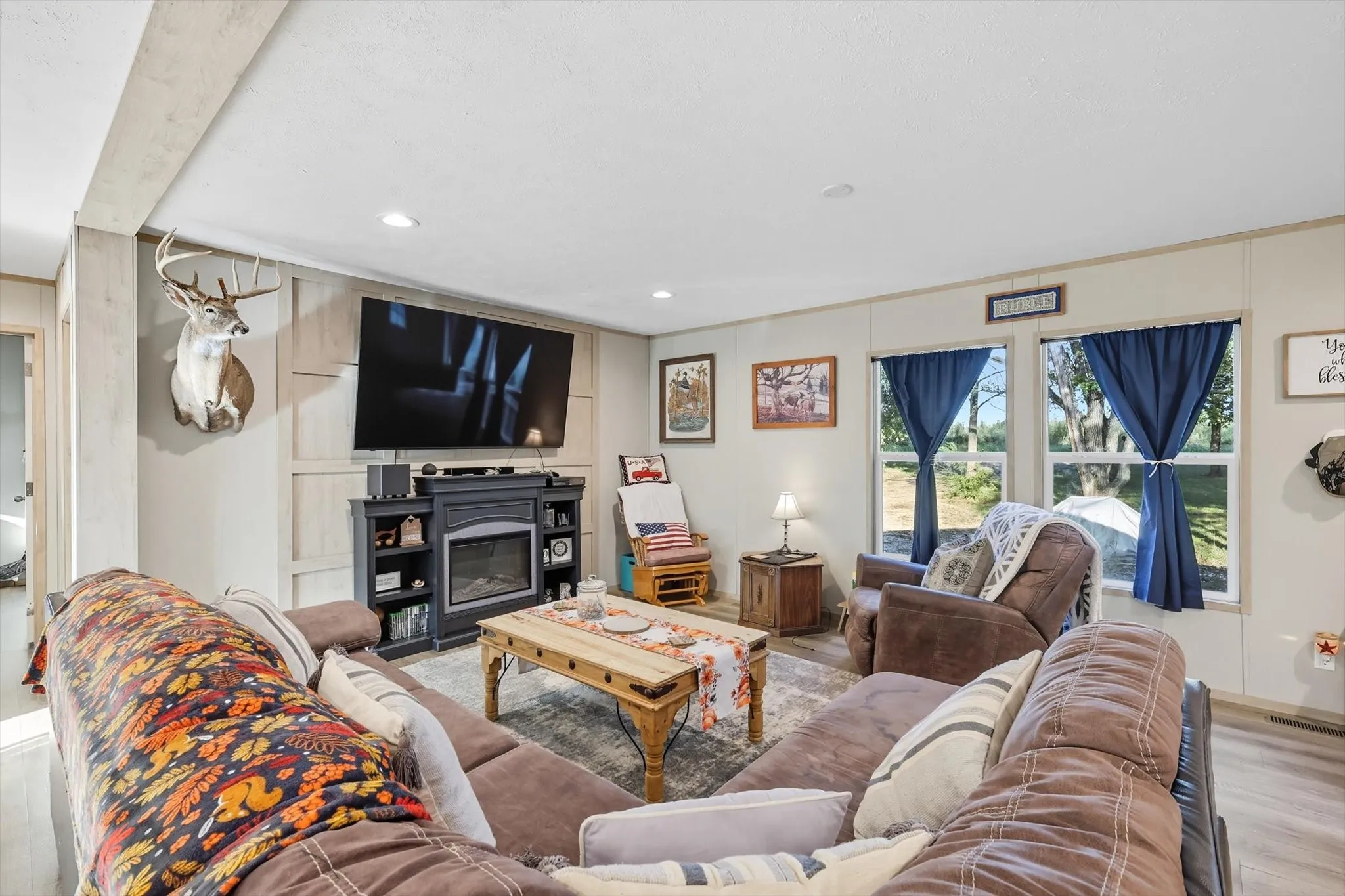 Living room with wood finished floors, recessed lighting, and a glass covered fireplace