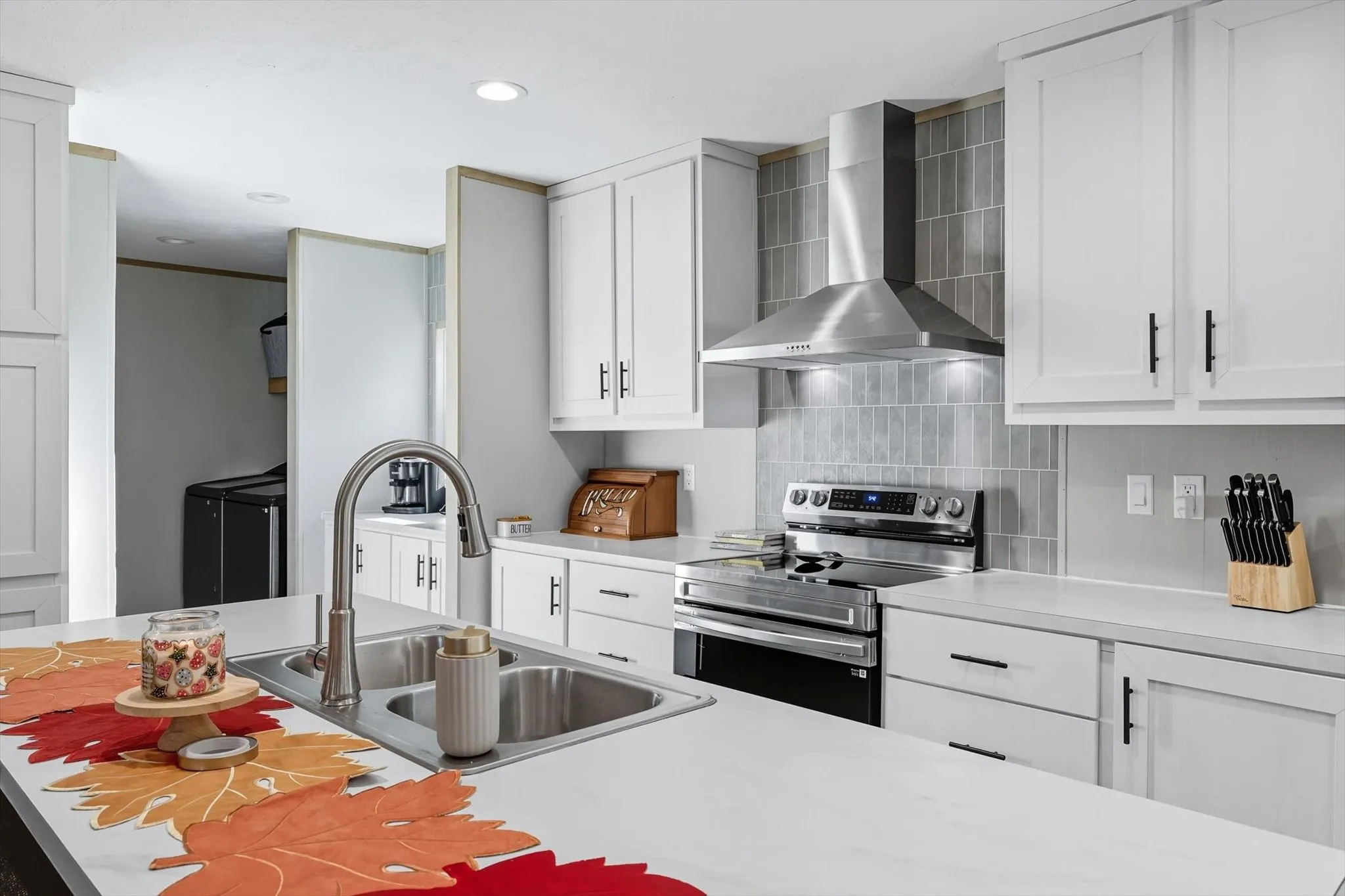 Kitchen featuring light countertops, stainless steel electric stove, wall chimney exhaust hood, white cabinetry, and recessed lighting