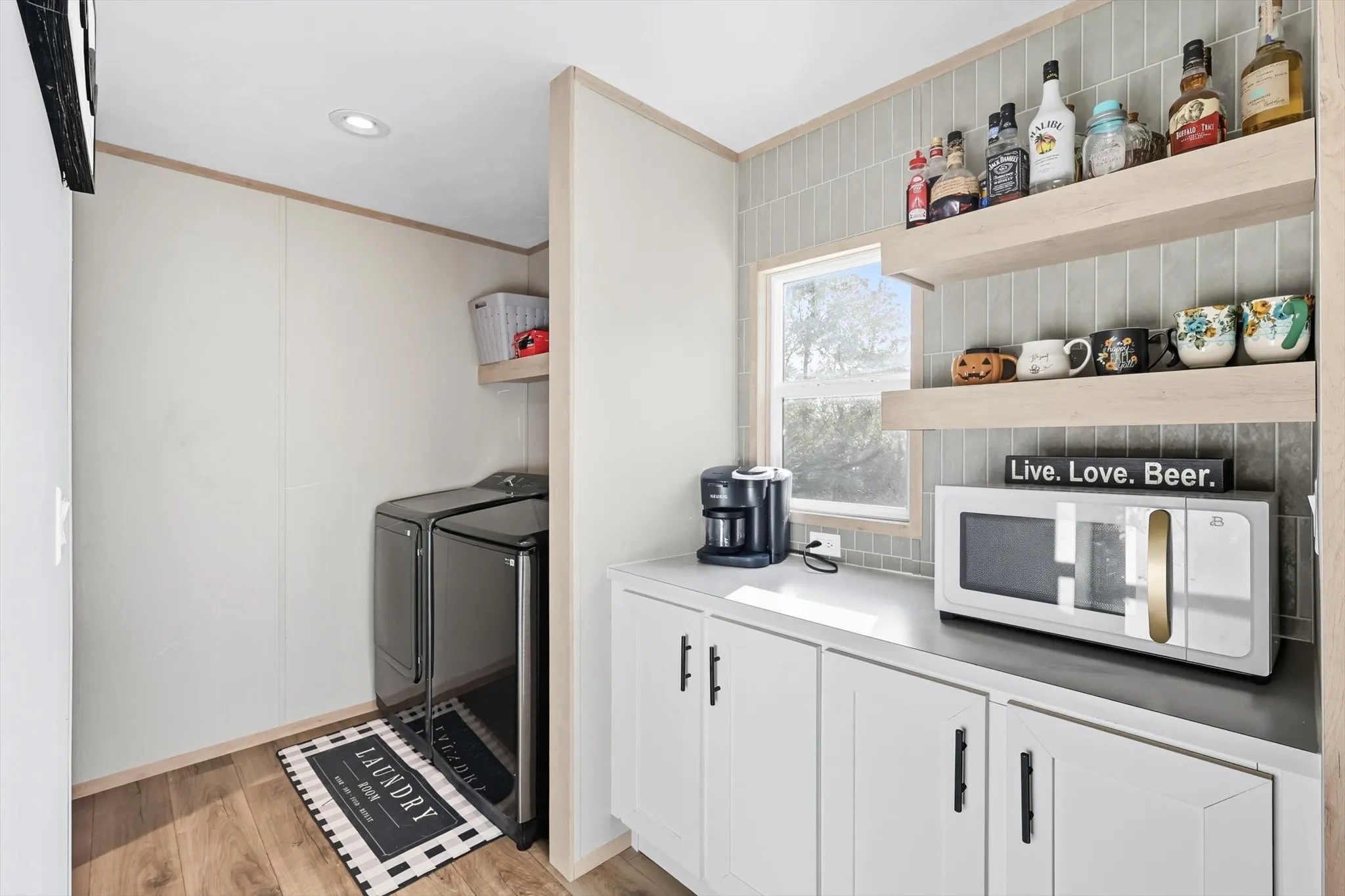 Kitchen with open shelves, white microwave, white cabinets, light wood-type flooring, and crown molding