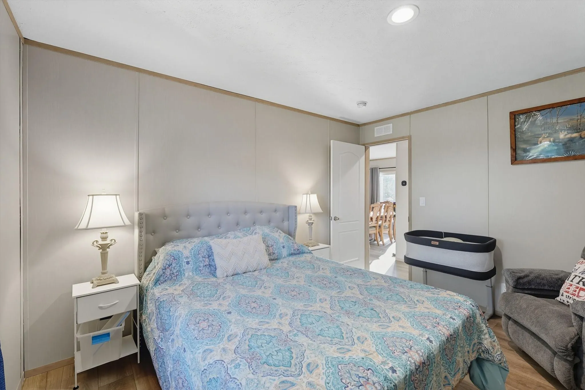 Bedroom with light wood-style flooring, ornamental molding, and a decorative wall