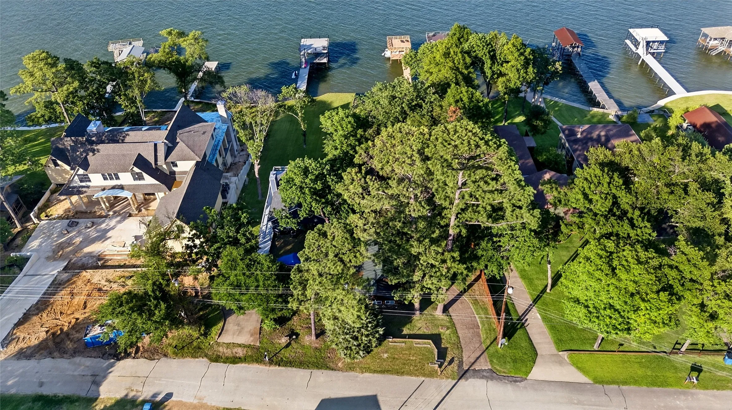 Waterfront property featuring extensive tree cover, a multi-gabled roofline, and a private boat dock extending into the water.