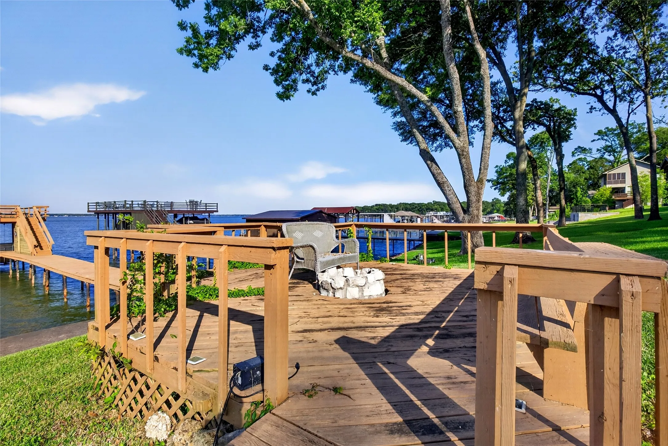 Waterfront wood-plank deck featuring a built-in bench, wood railing, and a fire pit.  Don't forget the S'mores fixings, kids and adults all love them.