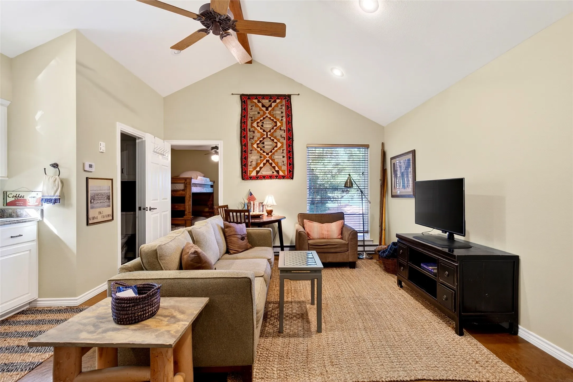 Cabin living space with vaulted ceiling featuring a ceiling fan, recessed lighting, stained concrete flooring, and a window with blinds