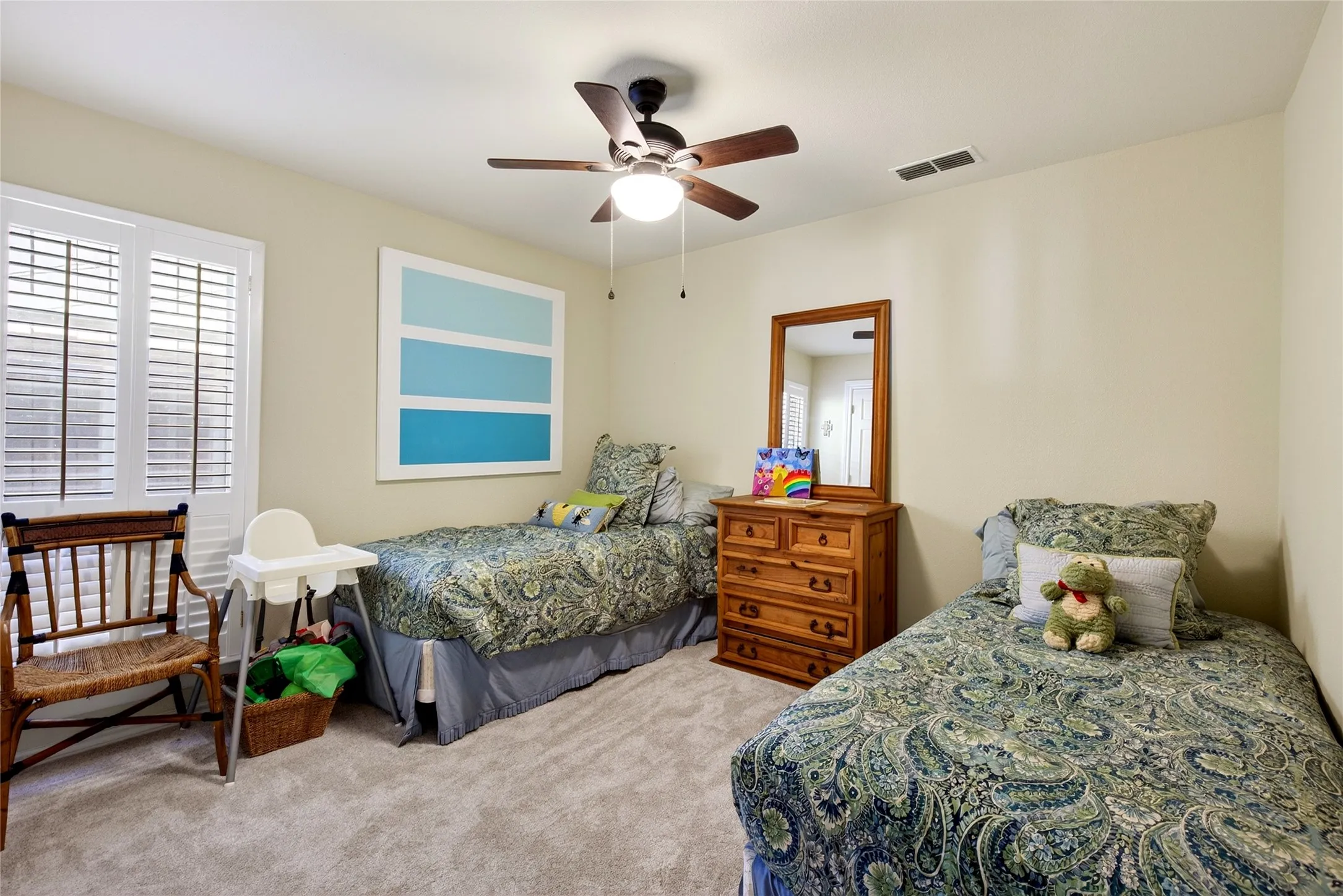 Carpeted bedroom featuring a ceiling fan with integrated lighting, a window with white plantation shutters, and a closet.