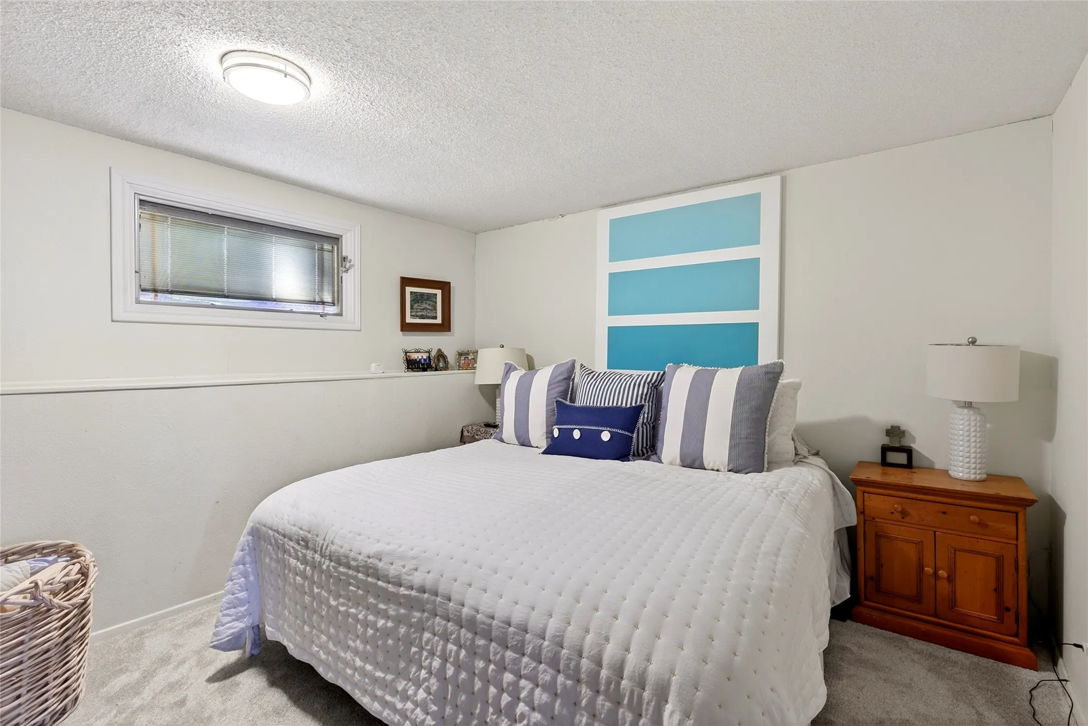 Primary Bedroom is a bright interior space featuring a recessed window with blinds, ceiling-mounted lighting, light-toned walls, and grey carpeting.