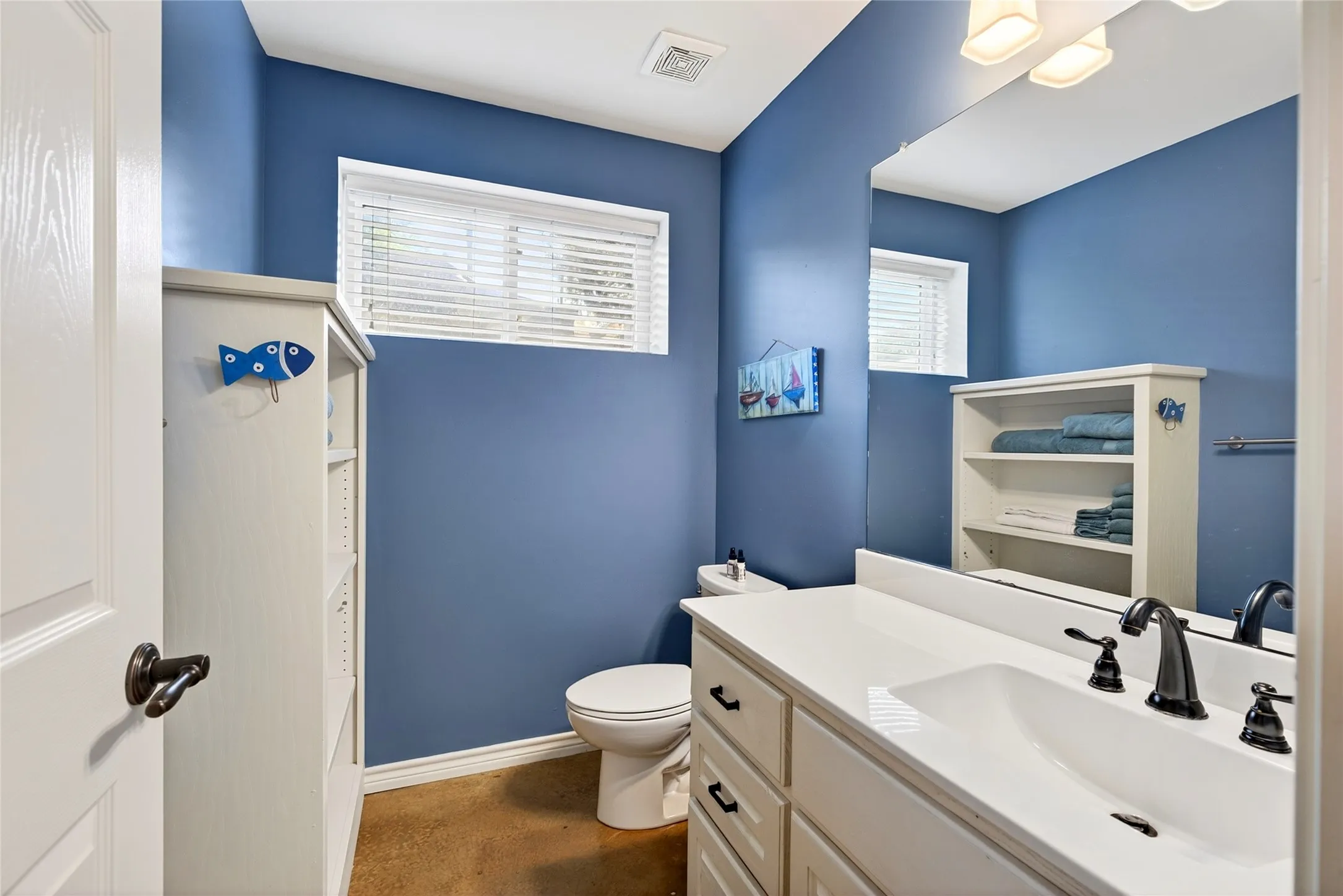 Cabin 1st half bathroom featuring a white vanity with an integrated sink, dark bronze-finish fixtures, and large wall-mounted mirror.