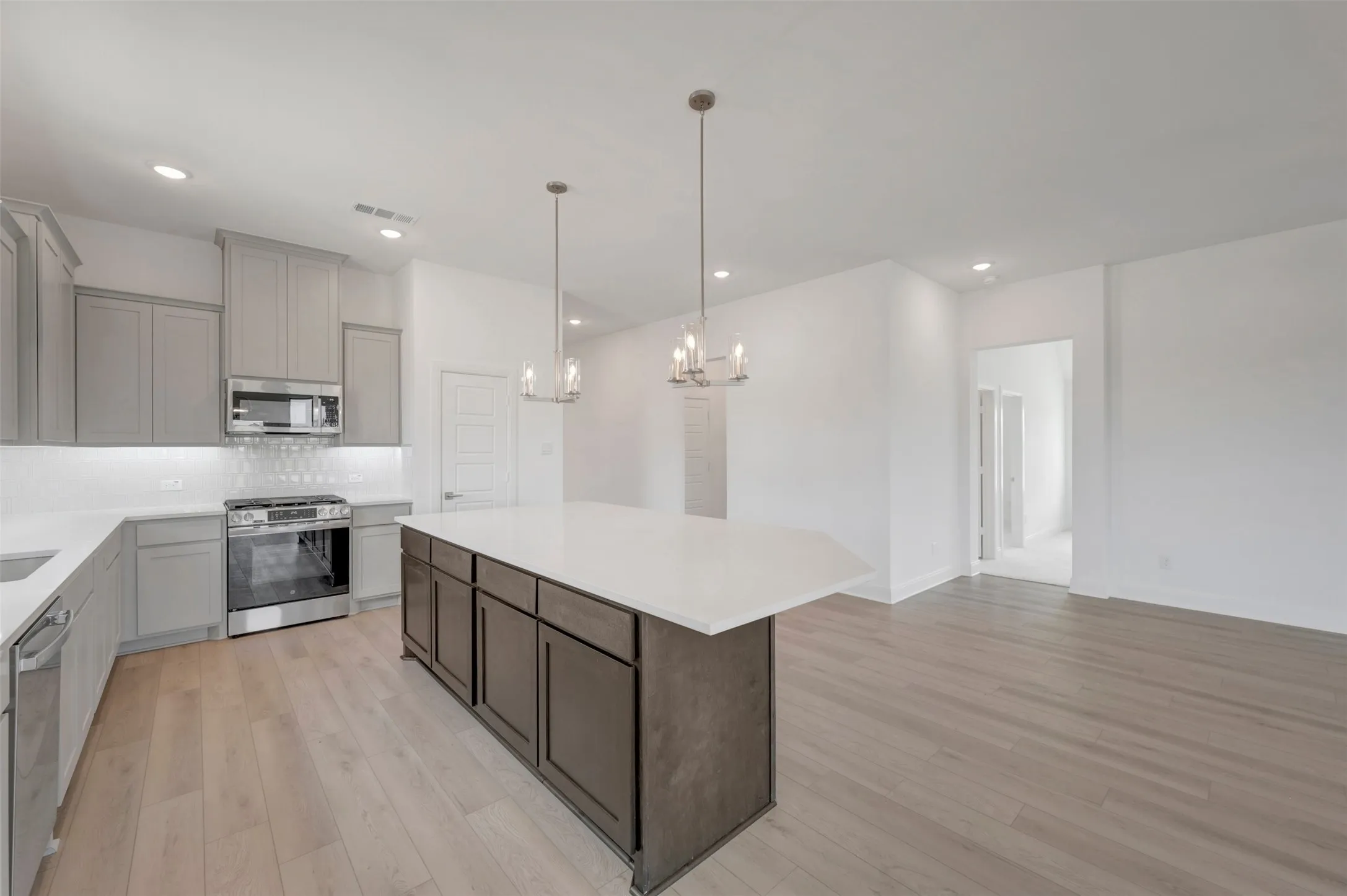 Kitchen featuring light gray cabinetry, stainless steel appliances, white countertops, and a subway tile backsplash
