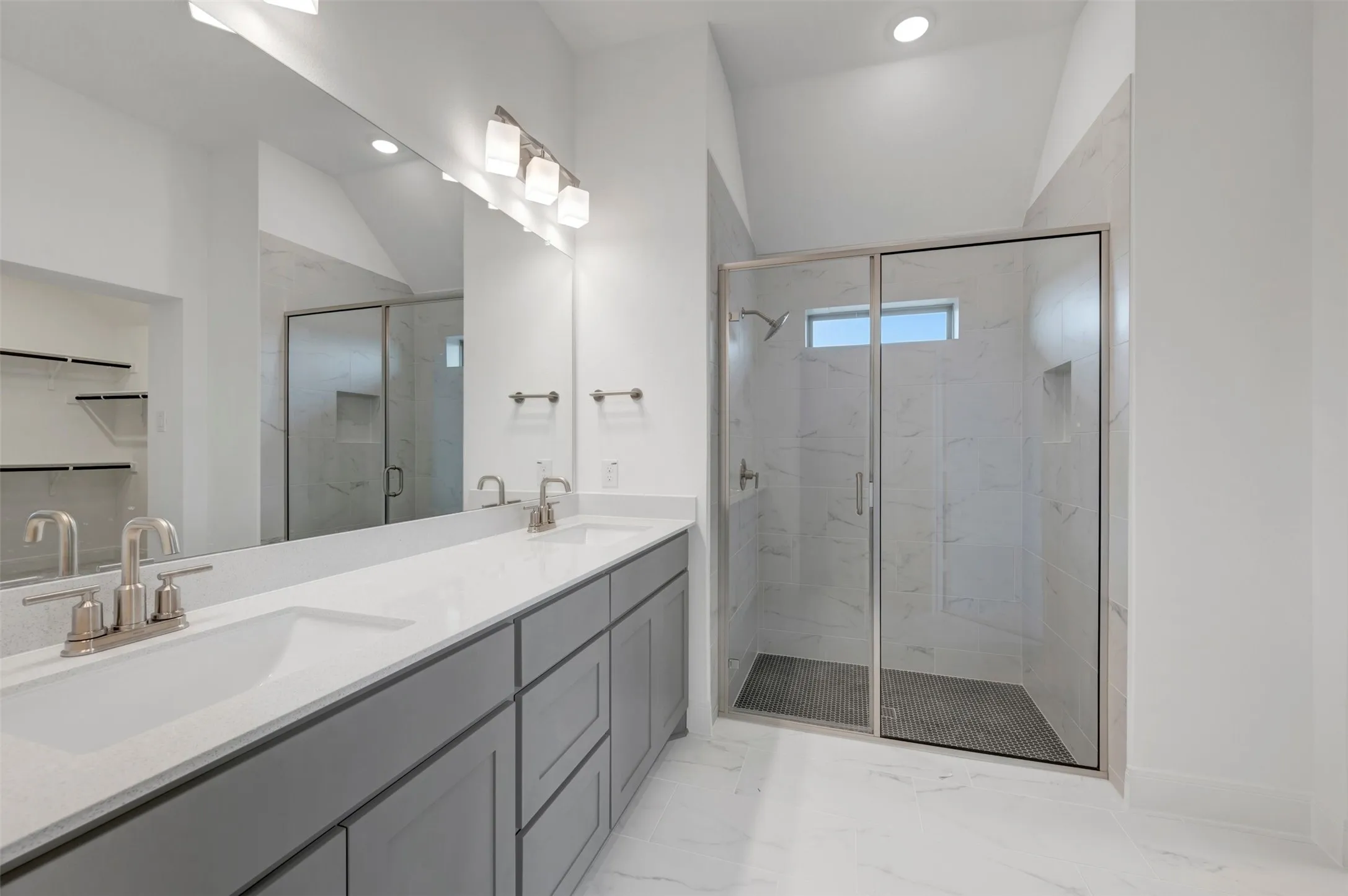 Double vanity with undermount sinks, stone countertops, and gray cabinetry