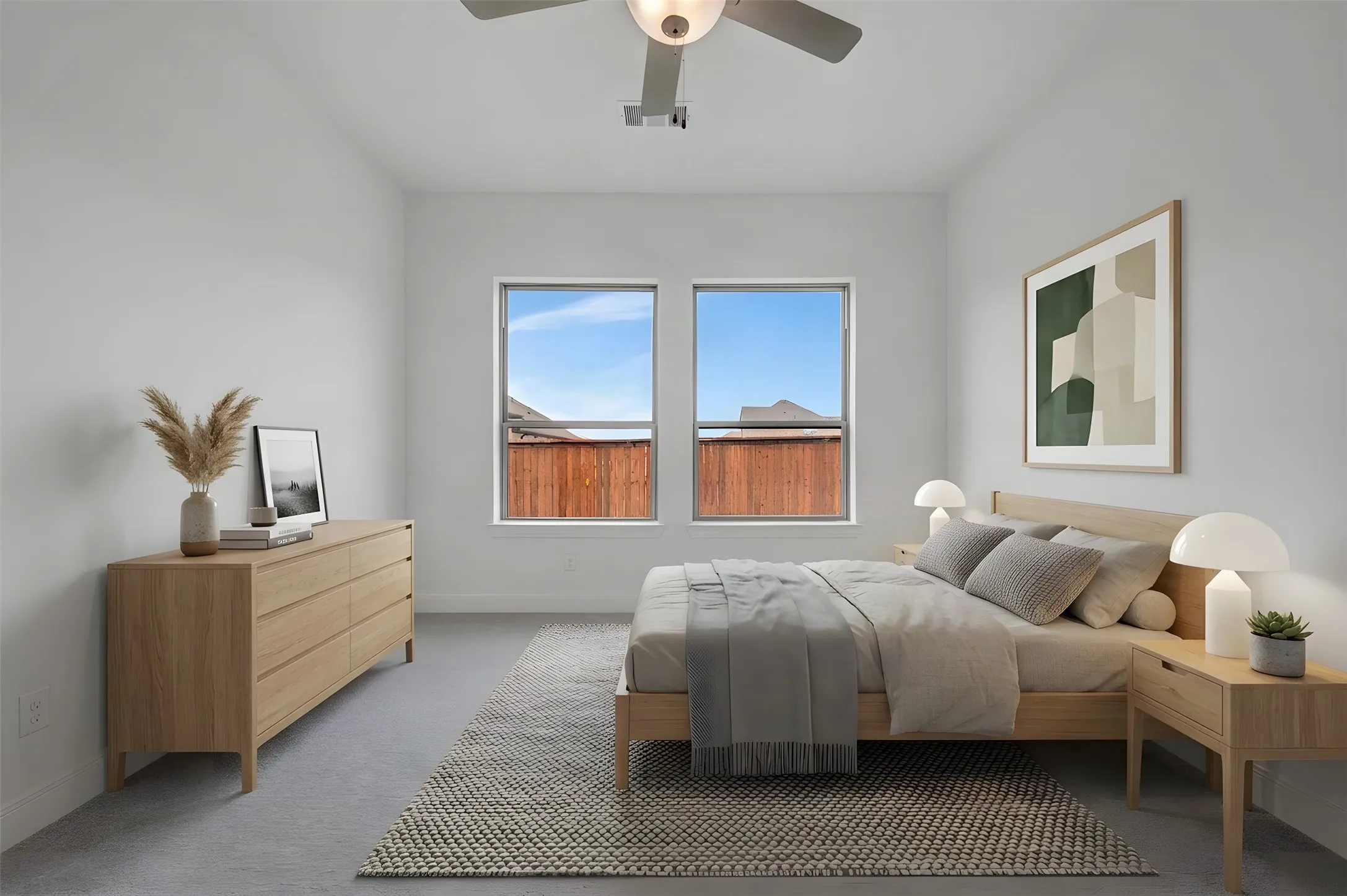 Bright bedroom featuring dual large windows with mountain vistas, light wood-finish flooring, neutral wall finishes, and a ceiling fan with integrated lighting