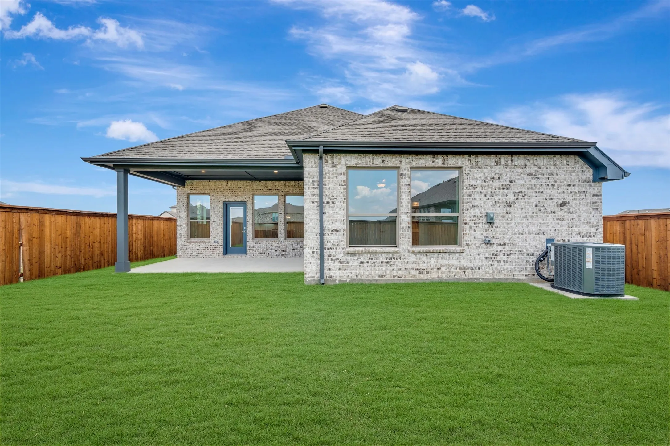 Expansive backyard featuring a manicured lawn, full privacy fencing, and a covered patio