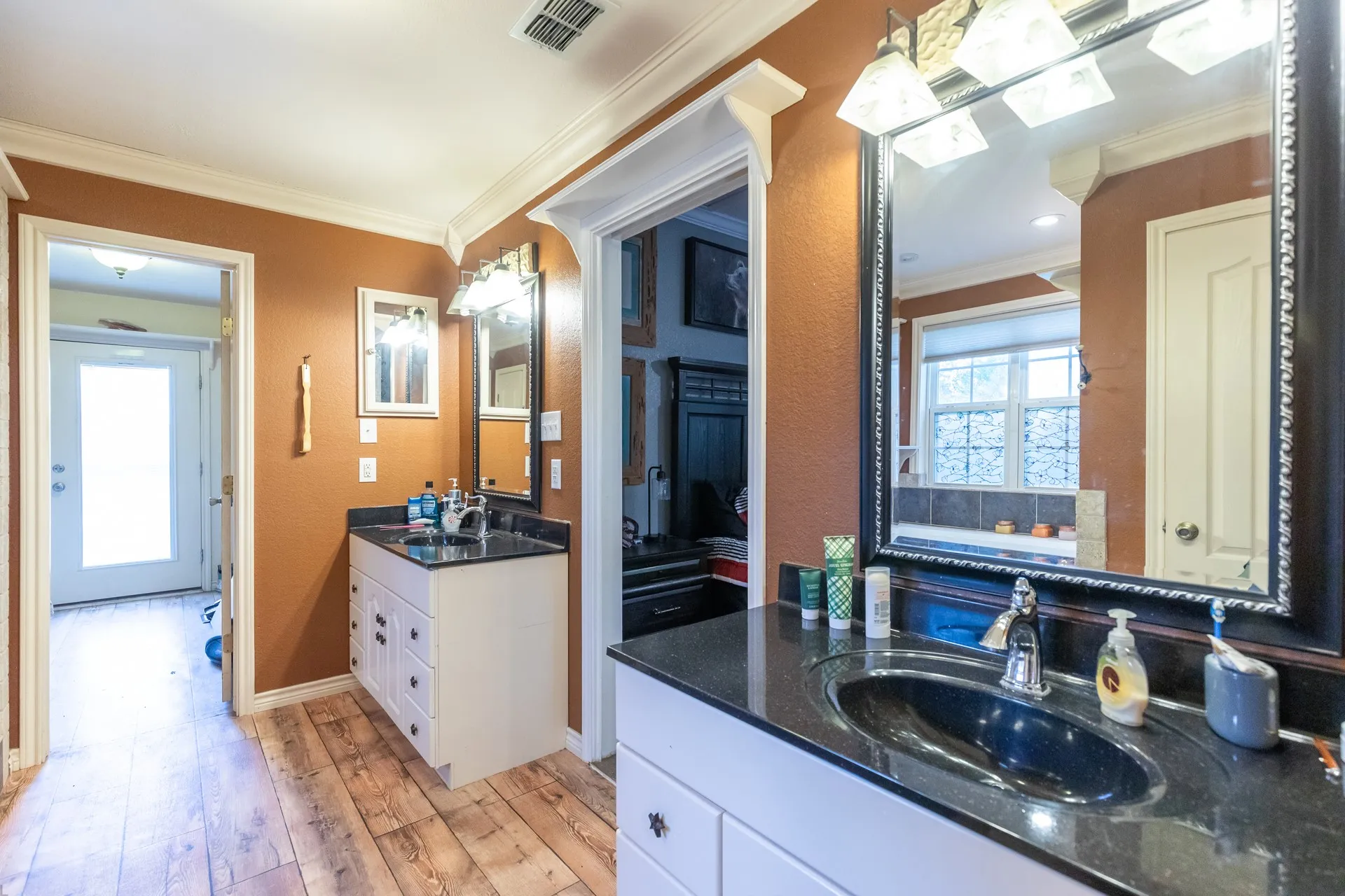 Dual vanity bathroom featuring wood-finish flooring and crown molding