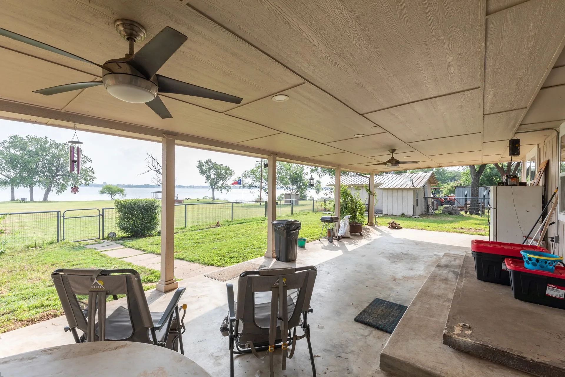 Covered patio with concrete flooring, multiple ceiling fans, and a partial outdoor kitchen setup