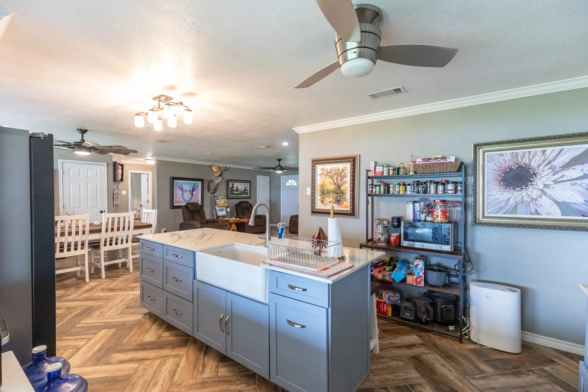 Kitchen island featuring a farmhouse sink, light blue cabinetry, and a light-colored countertop