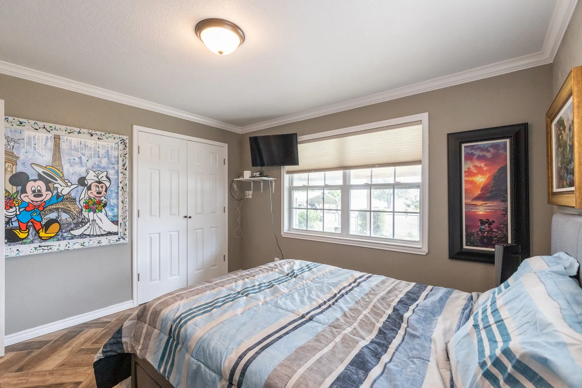 Interior room featuring wood-finish flooring in a herringbone pattern, crown molding, double-door closet, and a large window with blinds