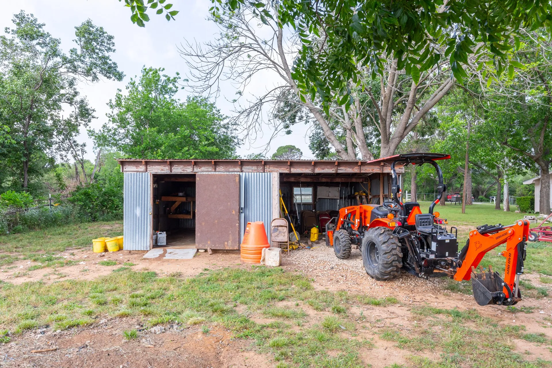 Corrugated metal utility shed with a wooden frame and covered parking area