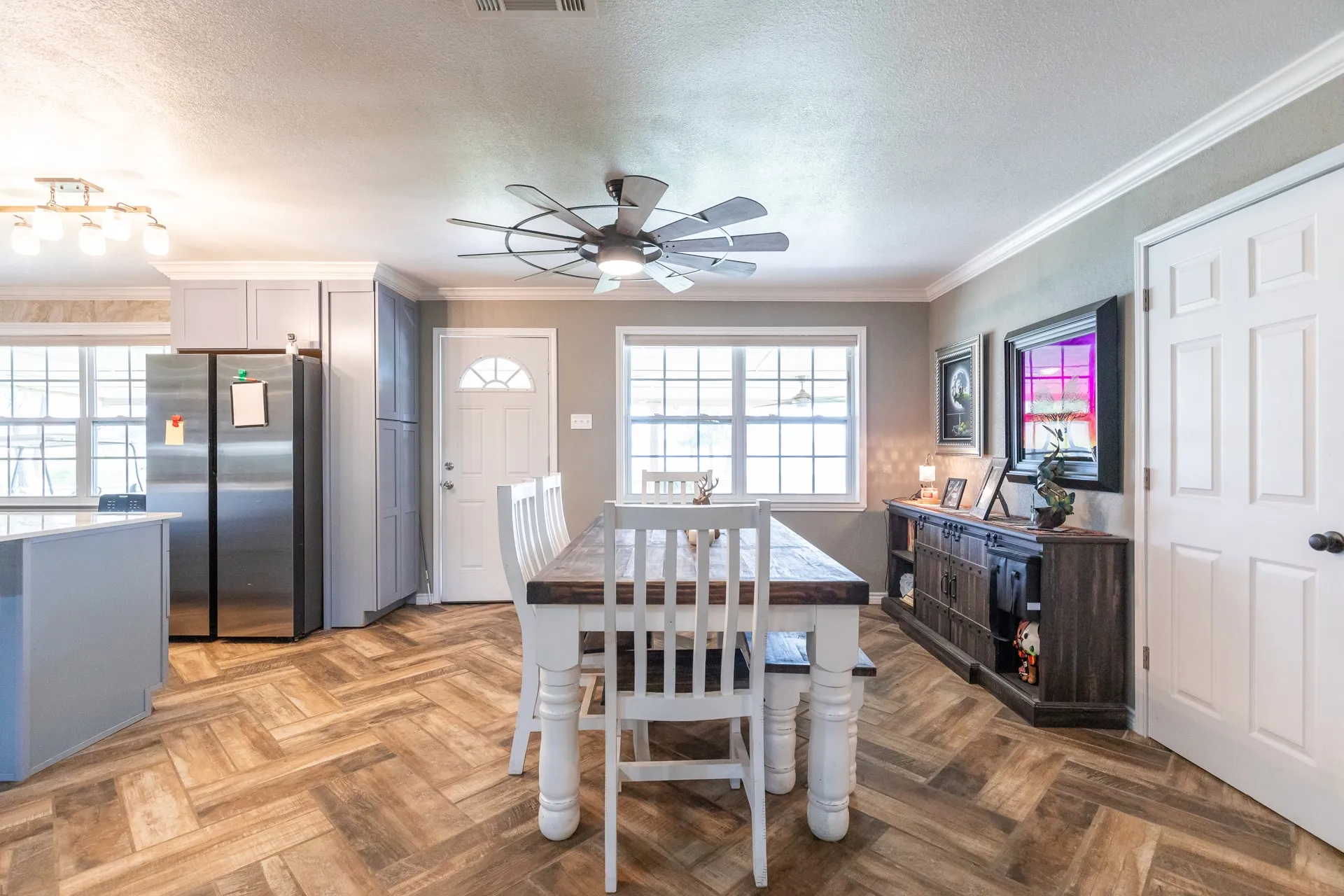Dining area featuring herringbone wood-finish flooring, a contemporary ceiling fan, and crown molding