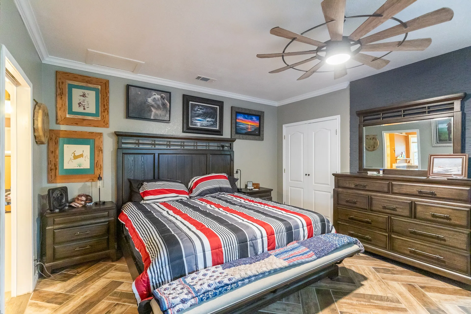 Spacious room featuring wood-finish flooring with a chevron pattern, a dark wood headboard, and crown molding