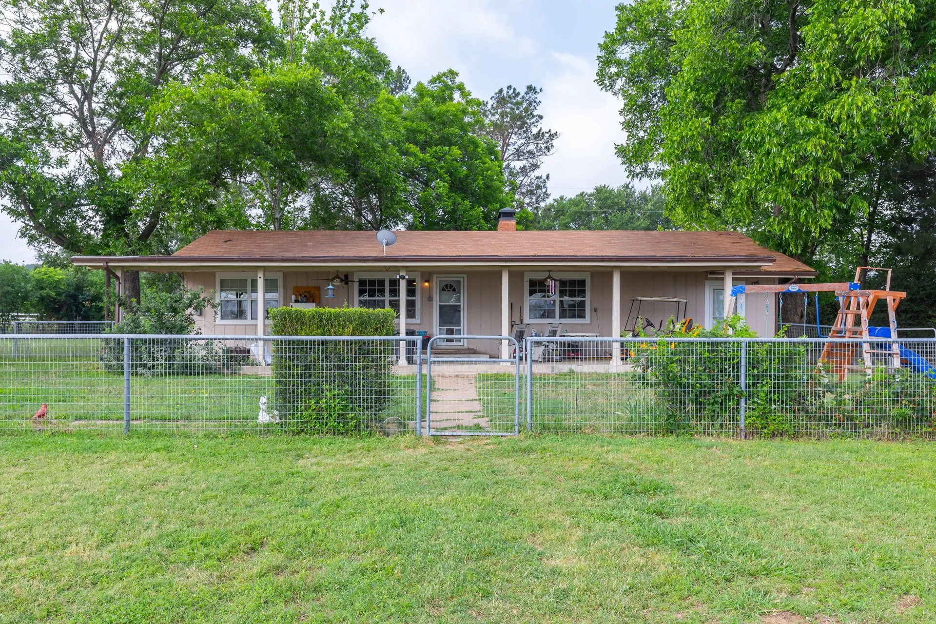 Ranch-style residence featuring a covered front porch with white columns, a neutral-toned exterior, and a brown shingle roof