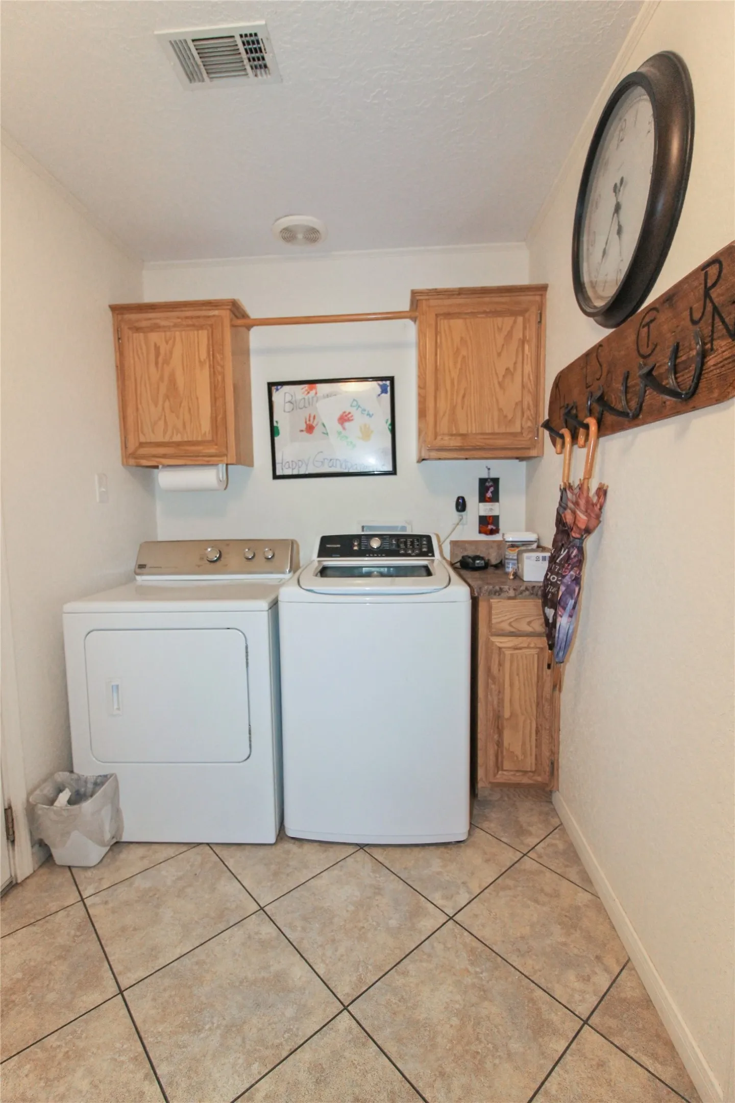 Laundry area featuring light wood-finish cabinetry, tile flooring, and a built-in hanging rod