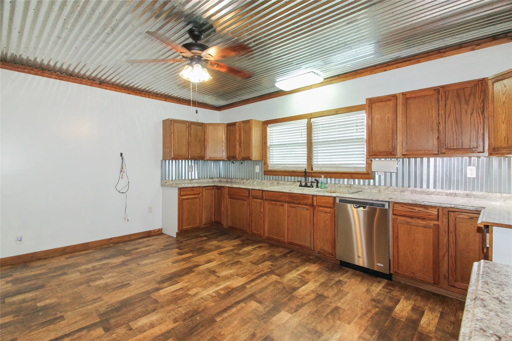 1936  HOUSE Kitchen featuring a corrugated metal ceiling, wood-finish flooring, wood cabinetry, stone-look countertops, and a stainless steel dishwasher