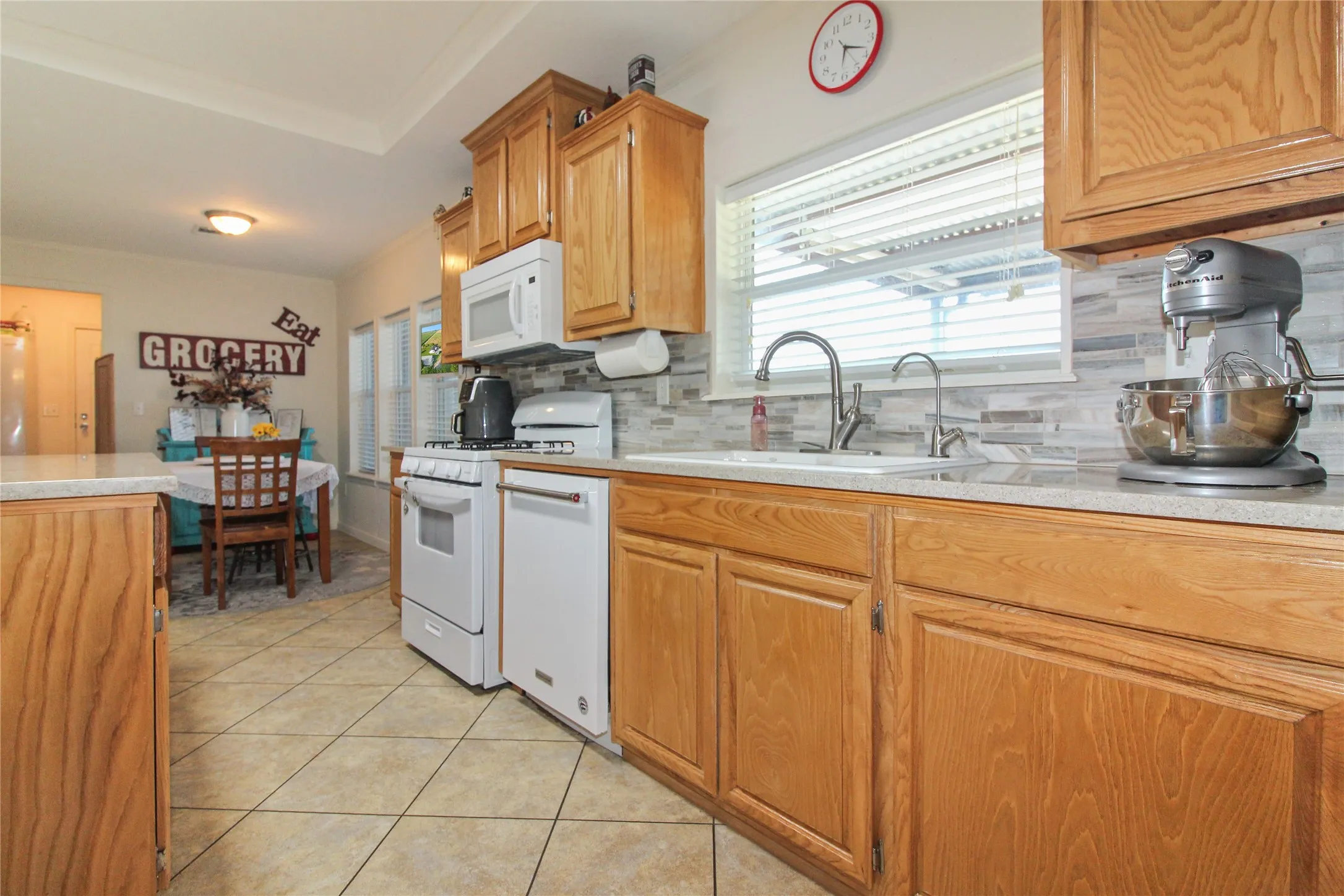 Kitchen featuring wood-finish cabinetry, light-toned countertops, and a full suite of white appliances
