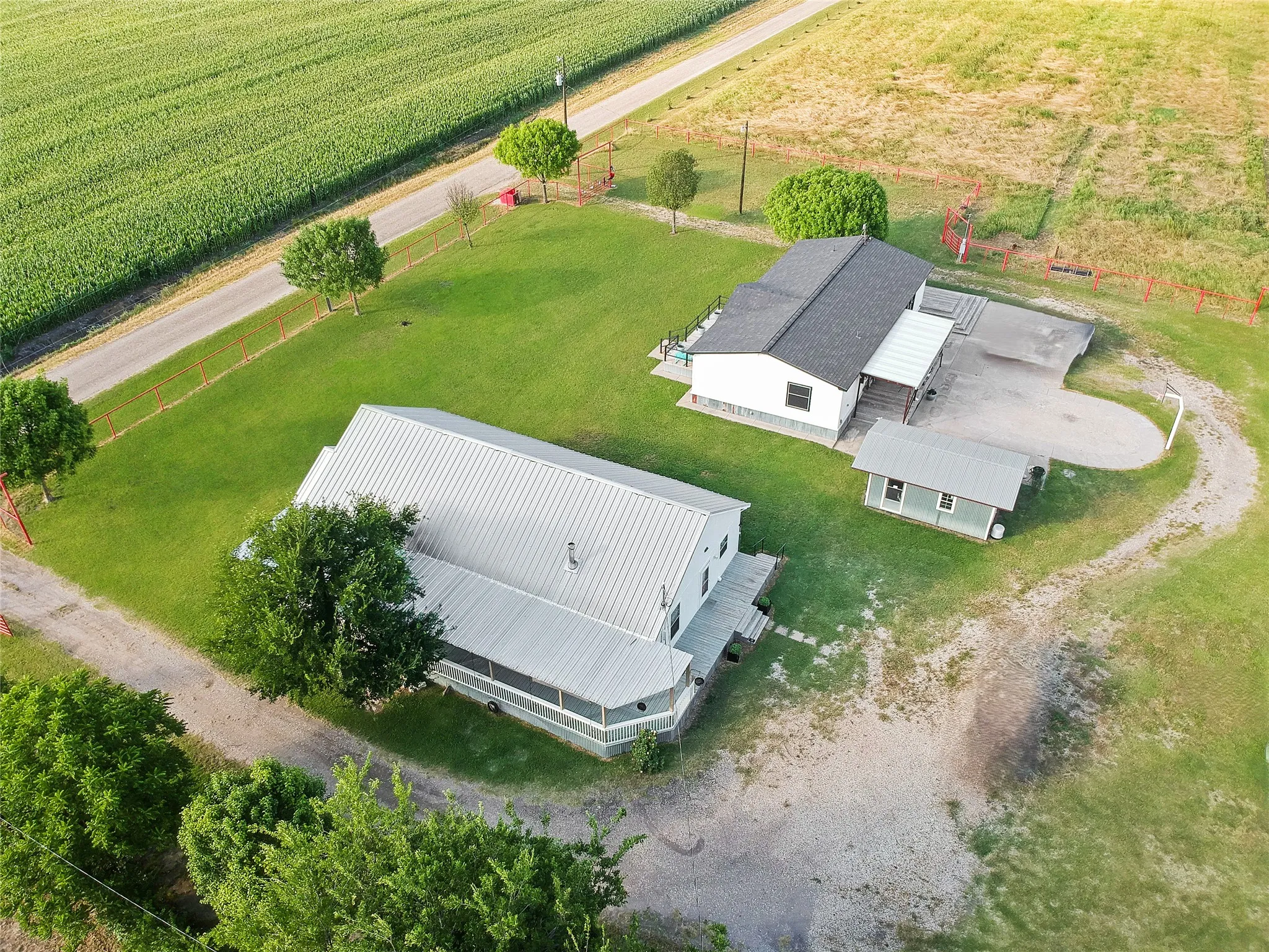 Expansive property featuring two structures with pitched roofs, a smaller auxiliary building, and a gravel driveway