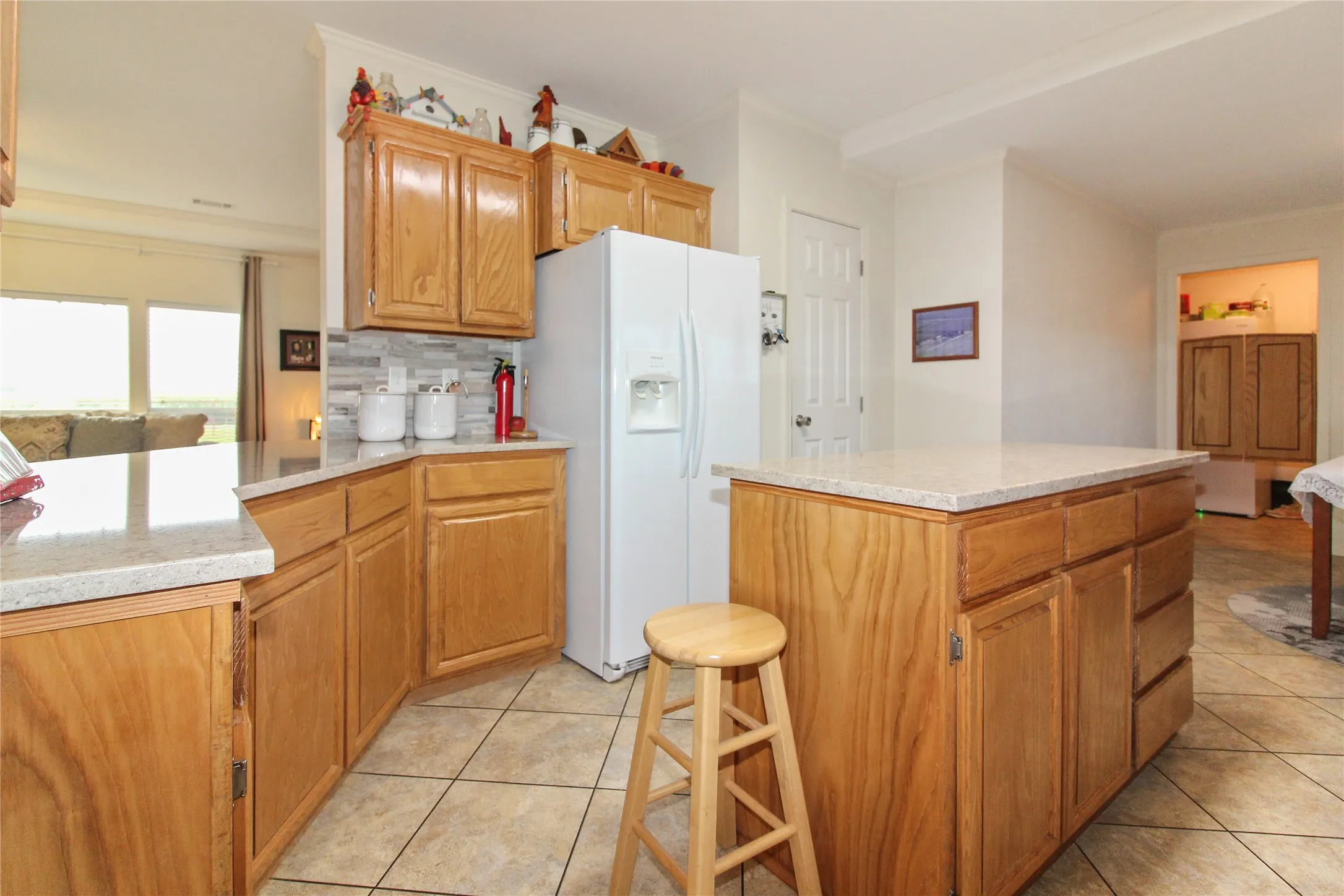 Kitchen featuring wood cabinetry, stone-look countertops, a tile backsplash, and tile flooring