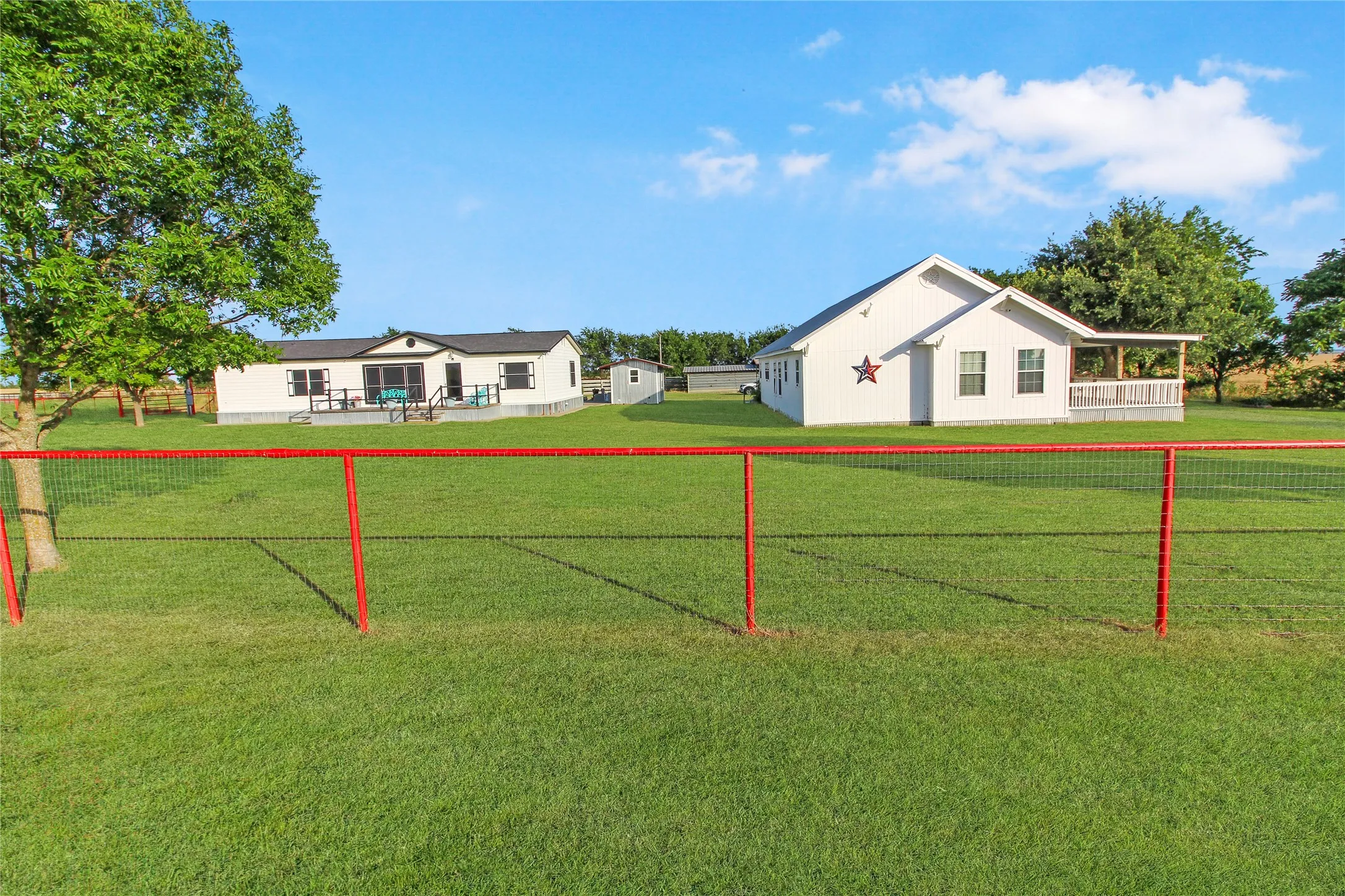 Expansive green lawn with a red-framed wire fence