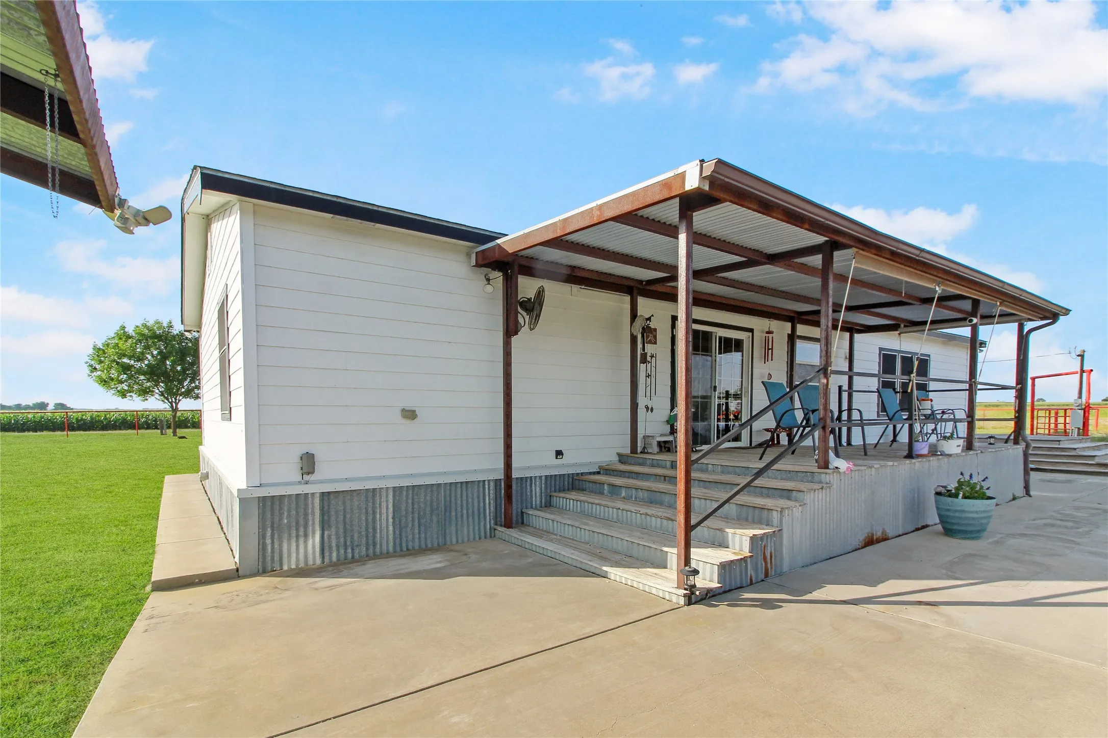 Expansive covered patio with concrete flooring, metal framing, and a corrugated metal roof