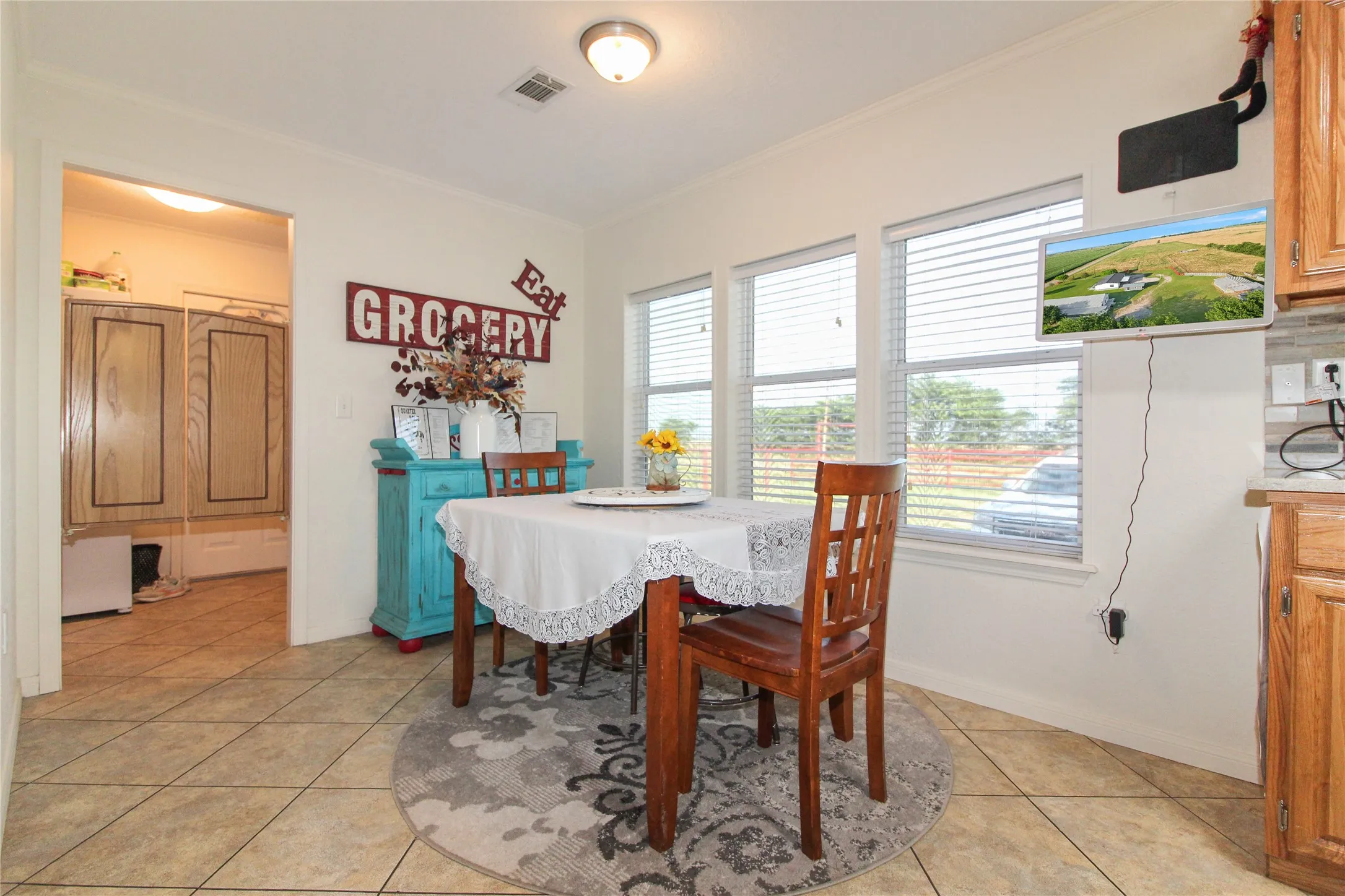 Dining area with three large windows, tile flooring, and a flush-mount ceiling light