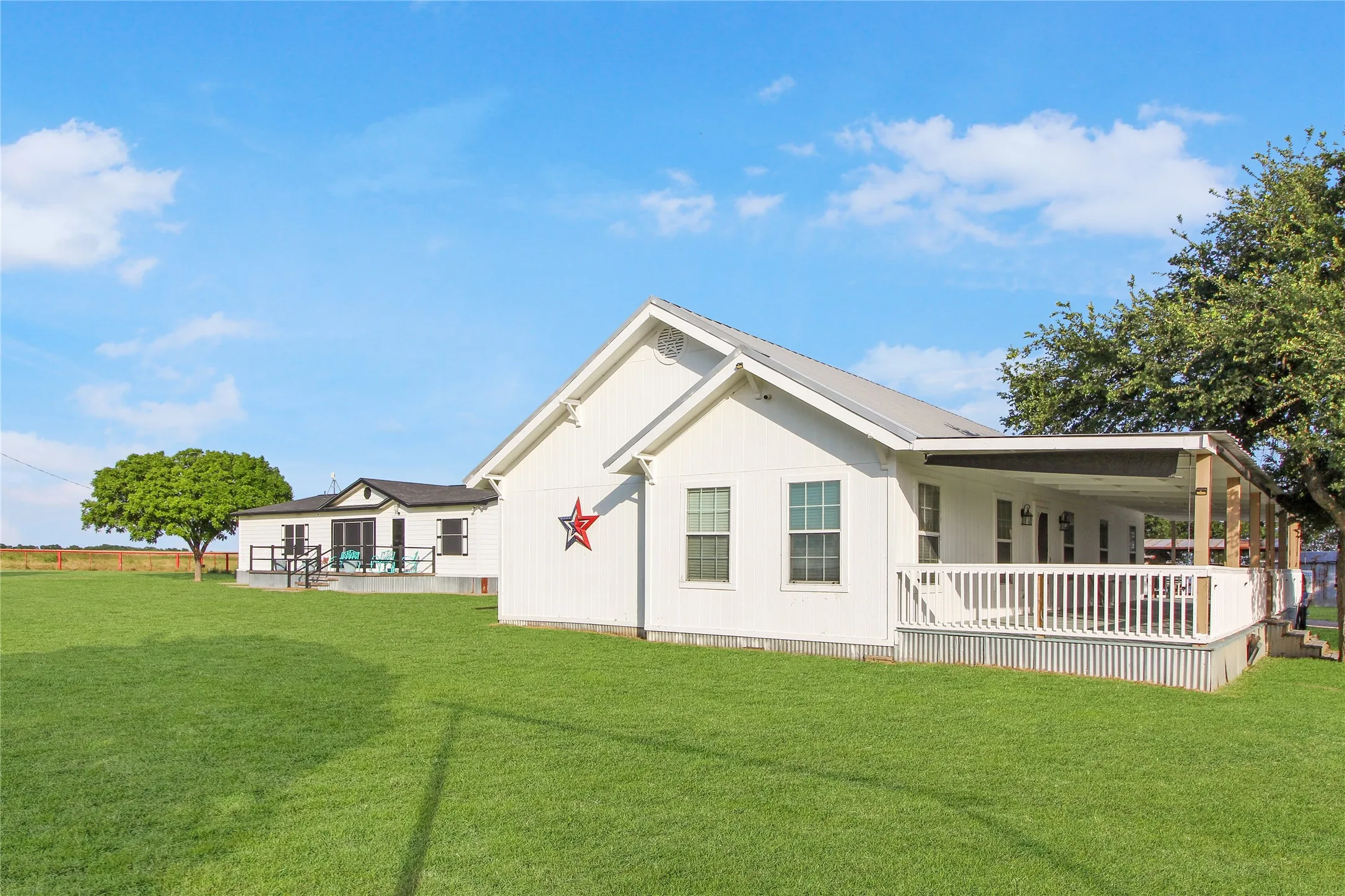 White-sided exterior with a metal roof and an expansive lawn