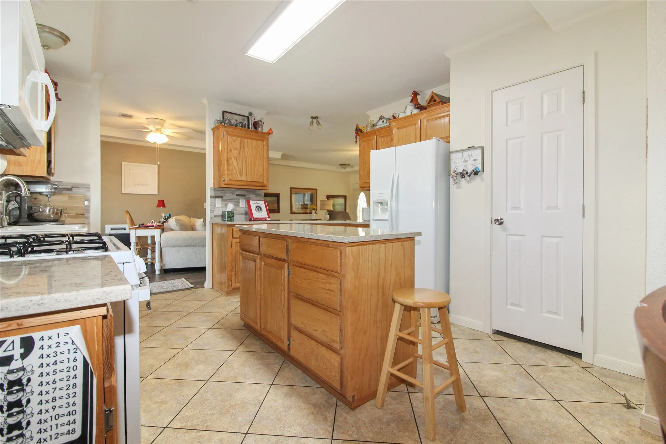 Kitchen featuring a central island with storage, light wood cabinetry, light-toned countertops, and tile flooring