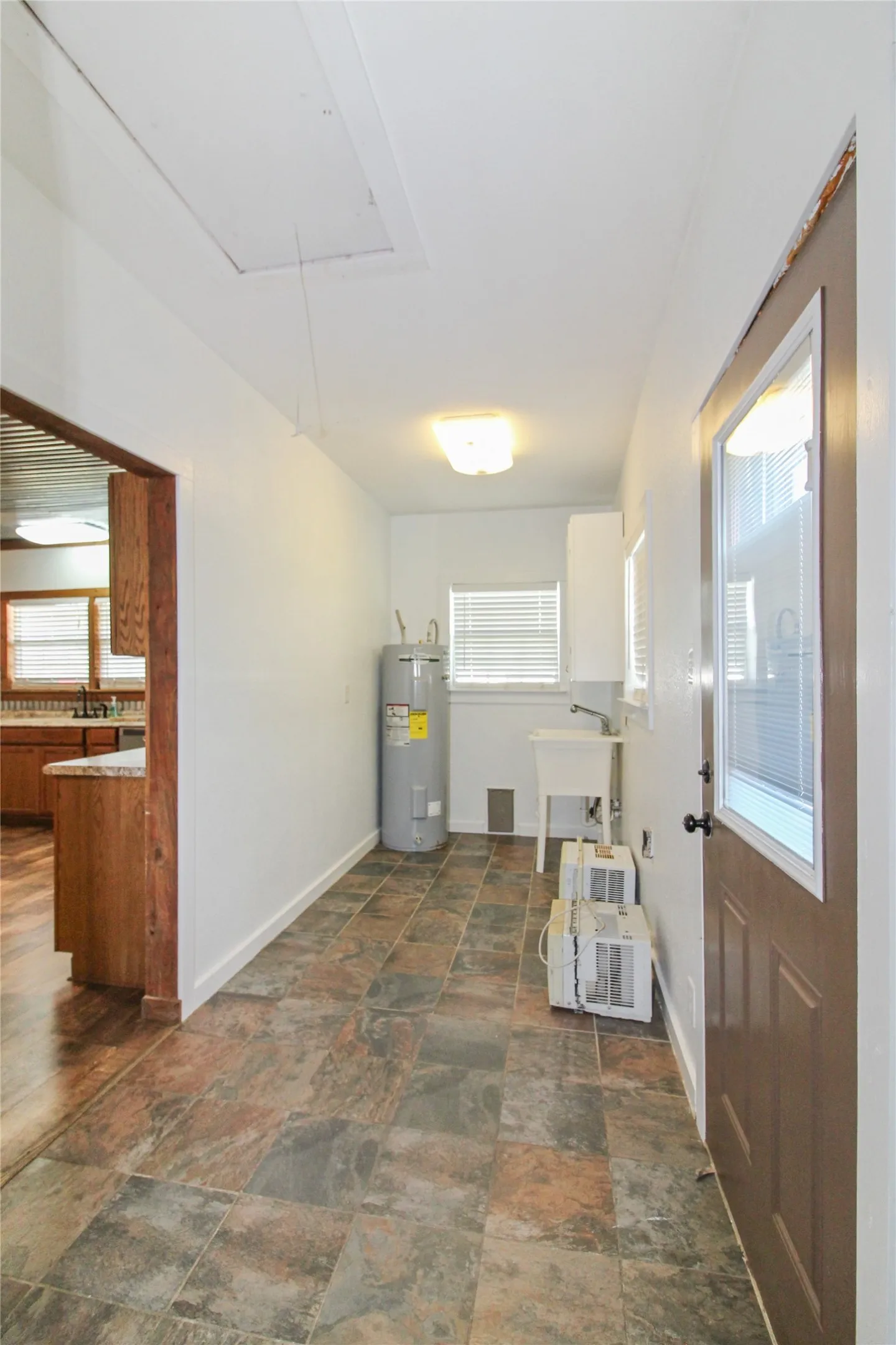 1936  HOUSE Utility area featuring a water heater, utility sink, and tiled flooring