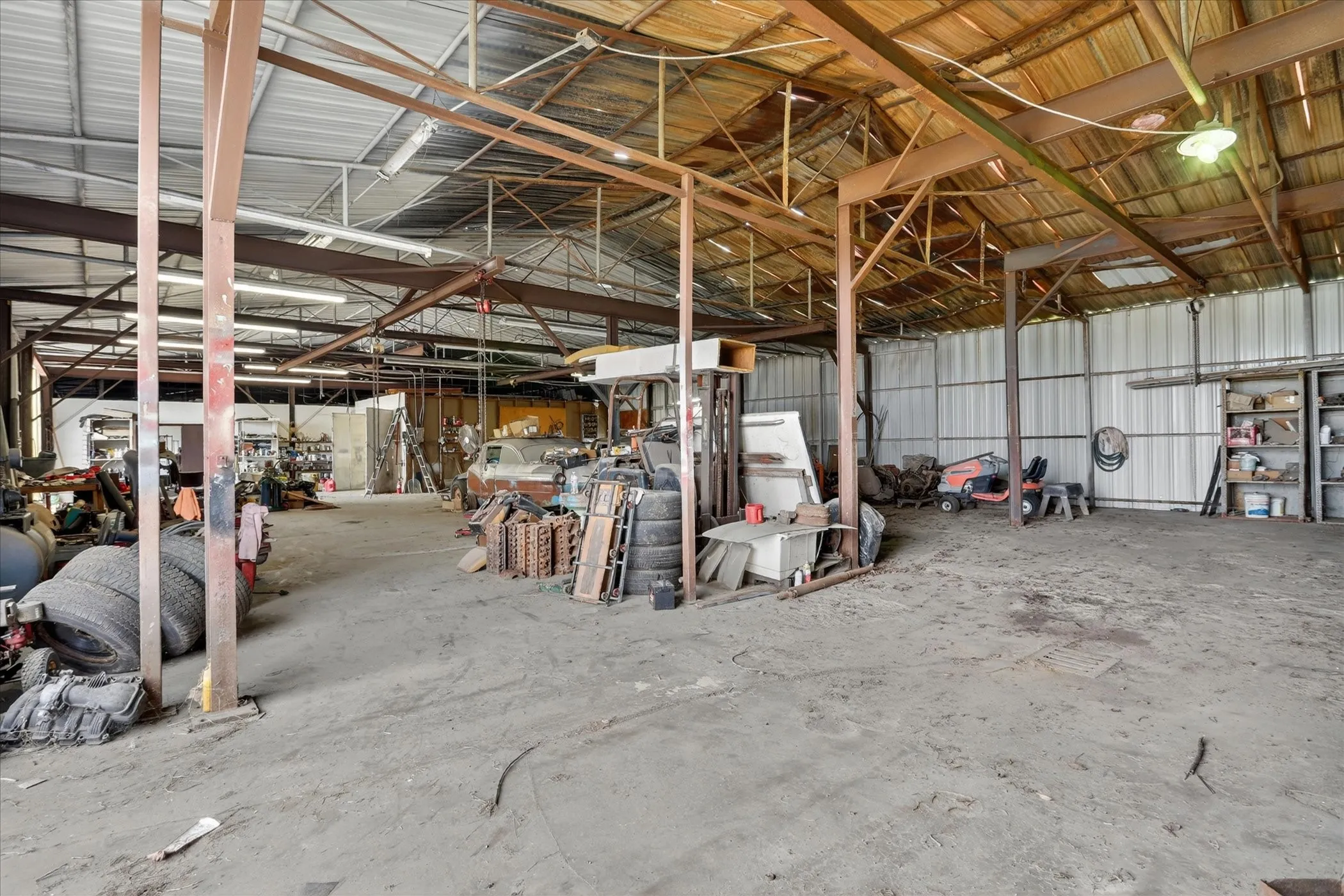Spacious warehouse interior featuring a high ceiling, exposed metal beam construction, corrugated metal wall panels, and a concrete floor