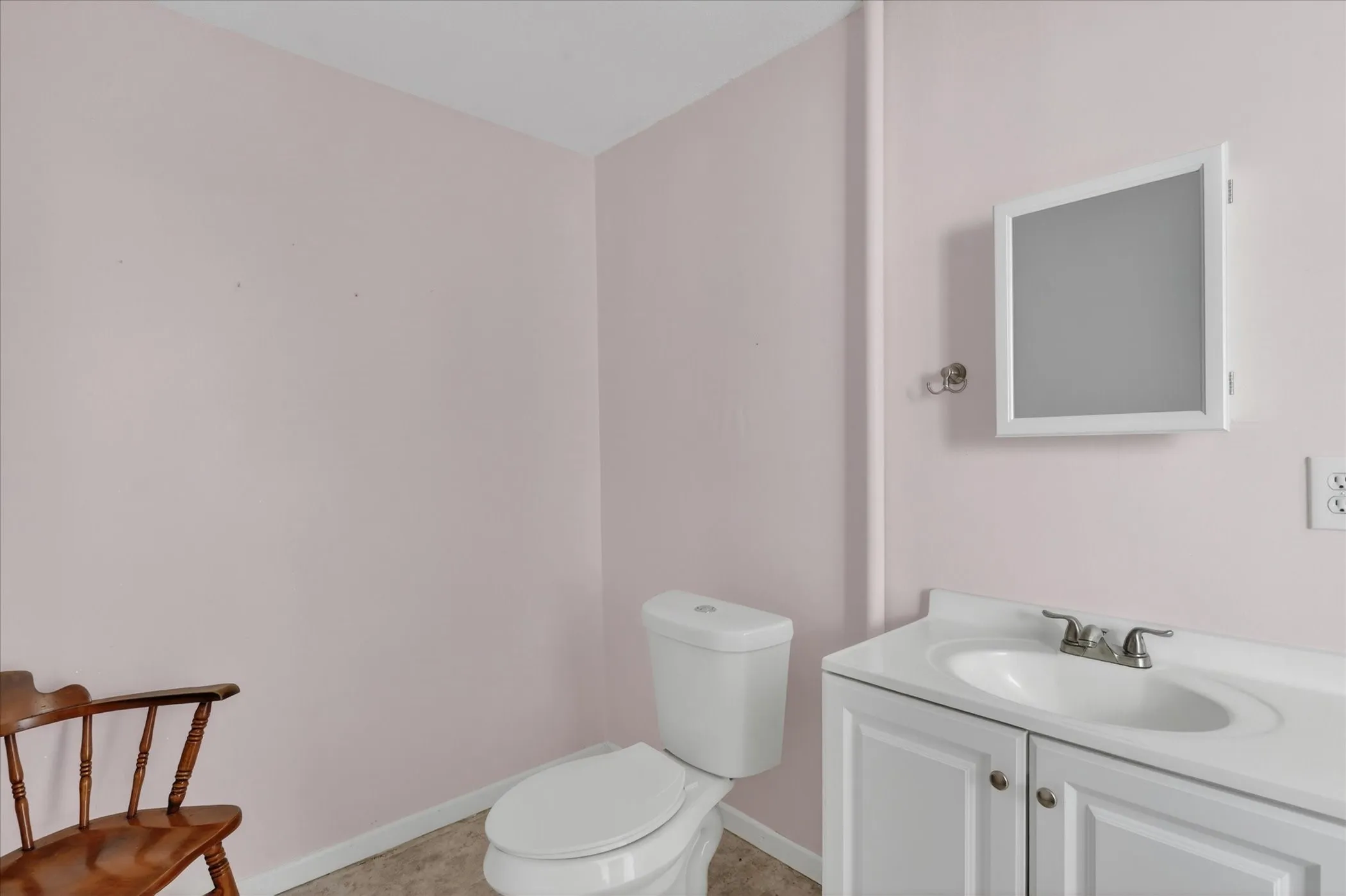 Bathroom featuring a white vanity with cabinet storage, a white medicine cabinet, and a white toilet